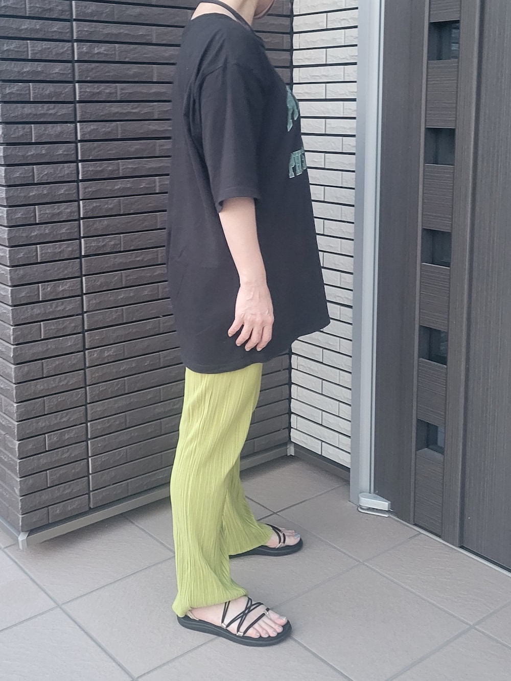 イエロー系のその他パンツ、ブラック系のTシャツ/カットソー、ブラック系のサンダルを着用したレディースの春コーディネートの2枚目の写真