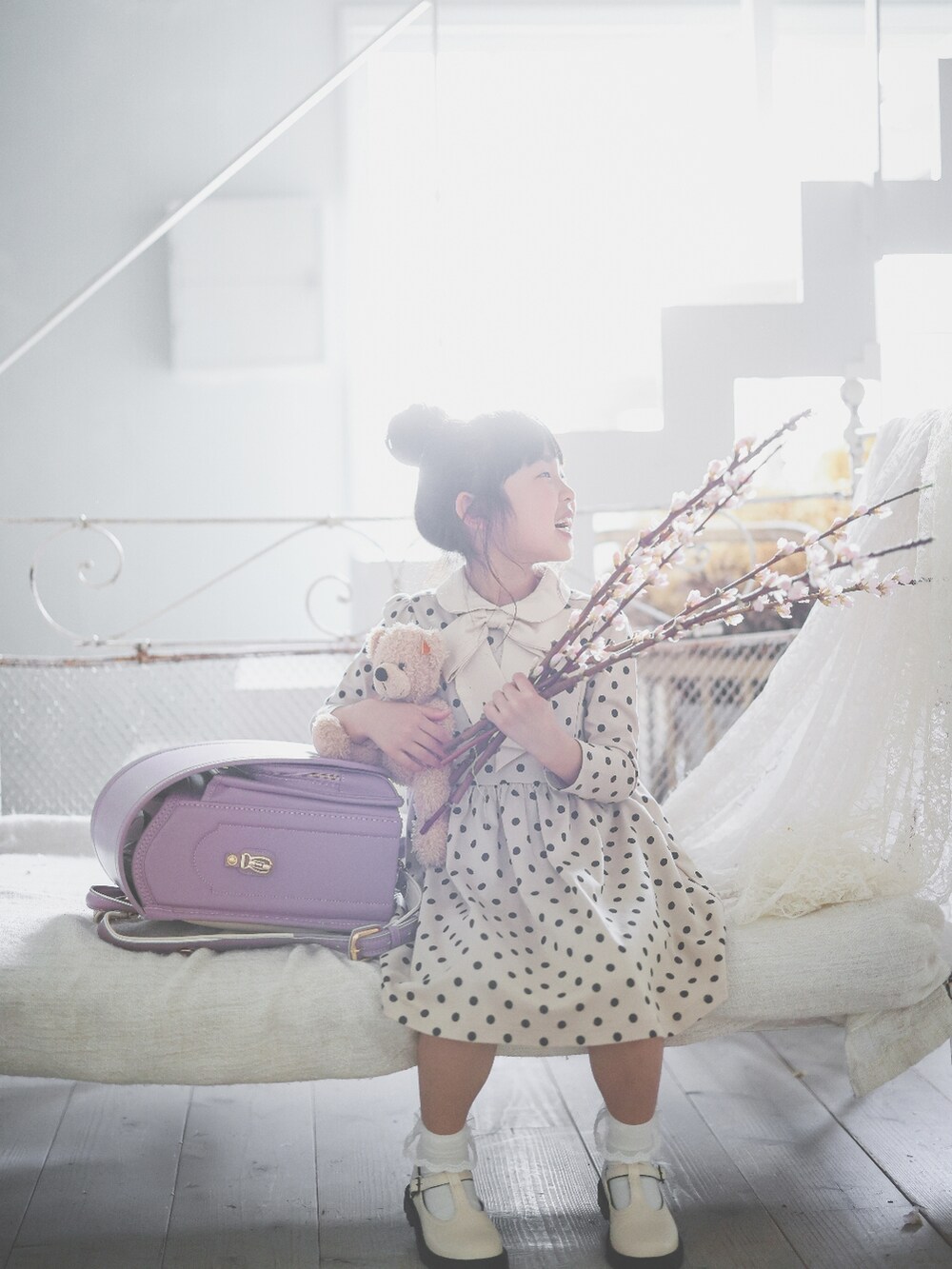 ベージュ系のワンピース、ホワイト系のシューズ、パープル系のランドセルを着用したキッズの春コーディネートの3枚目の写真
