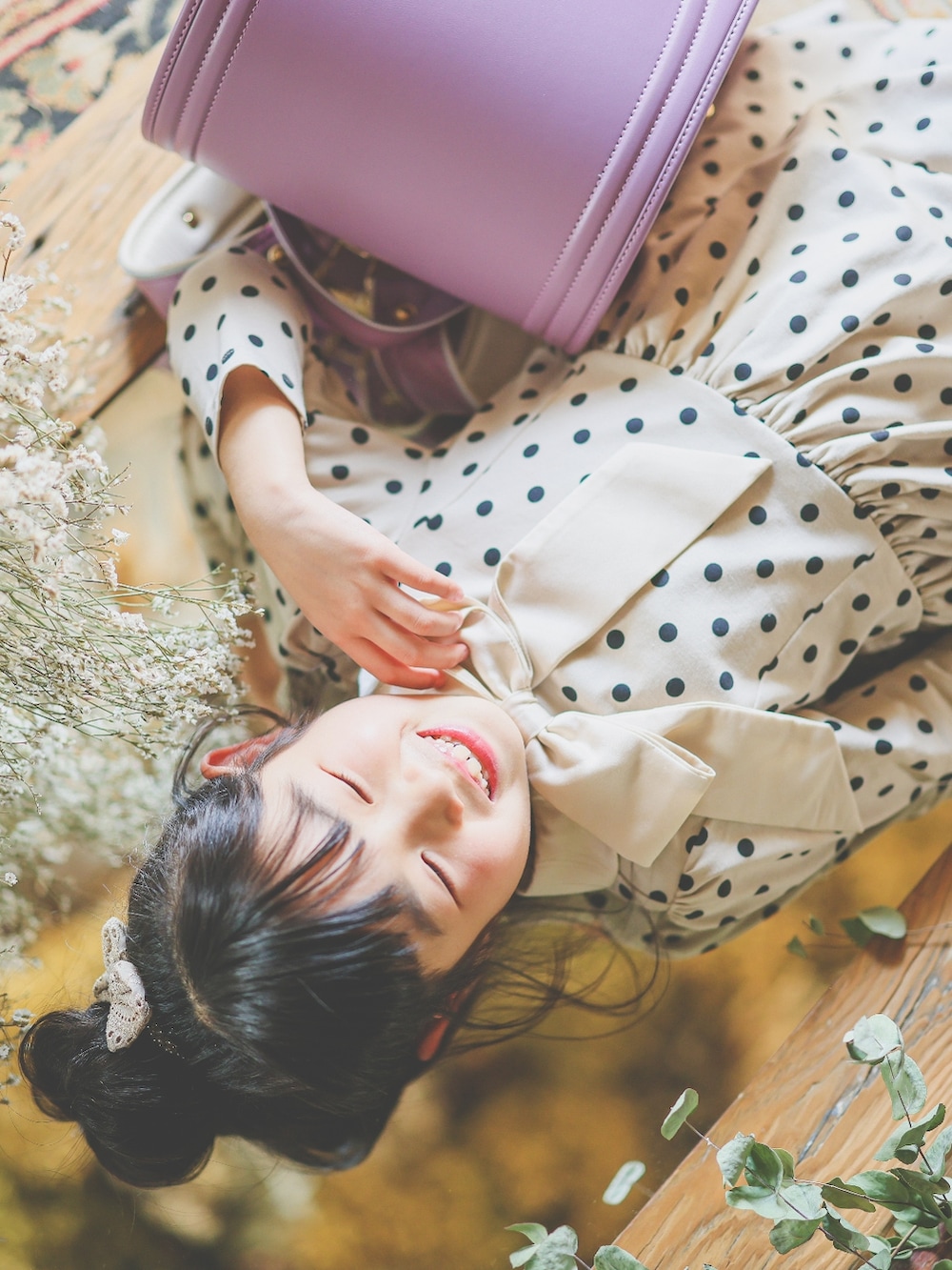 ホワイト系のシューズ、ベージュ系のワンピース、パープル系のランドセルを着用したキッズの春コーディネートの2枚目の写真