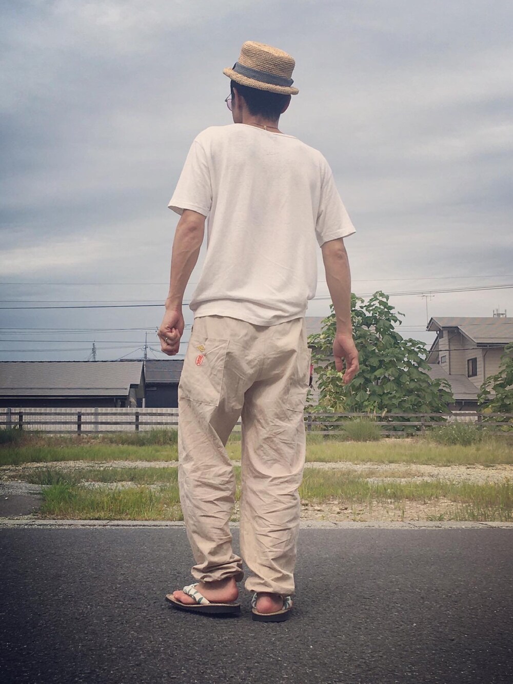 ホワイト系のTシャツ/カットソー、ベージュ系のパンツ、ベージュ系のサンダルを着用したメンズの秋コーディネートの3枚目の写真