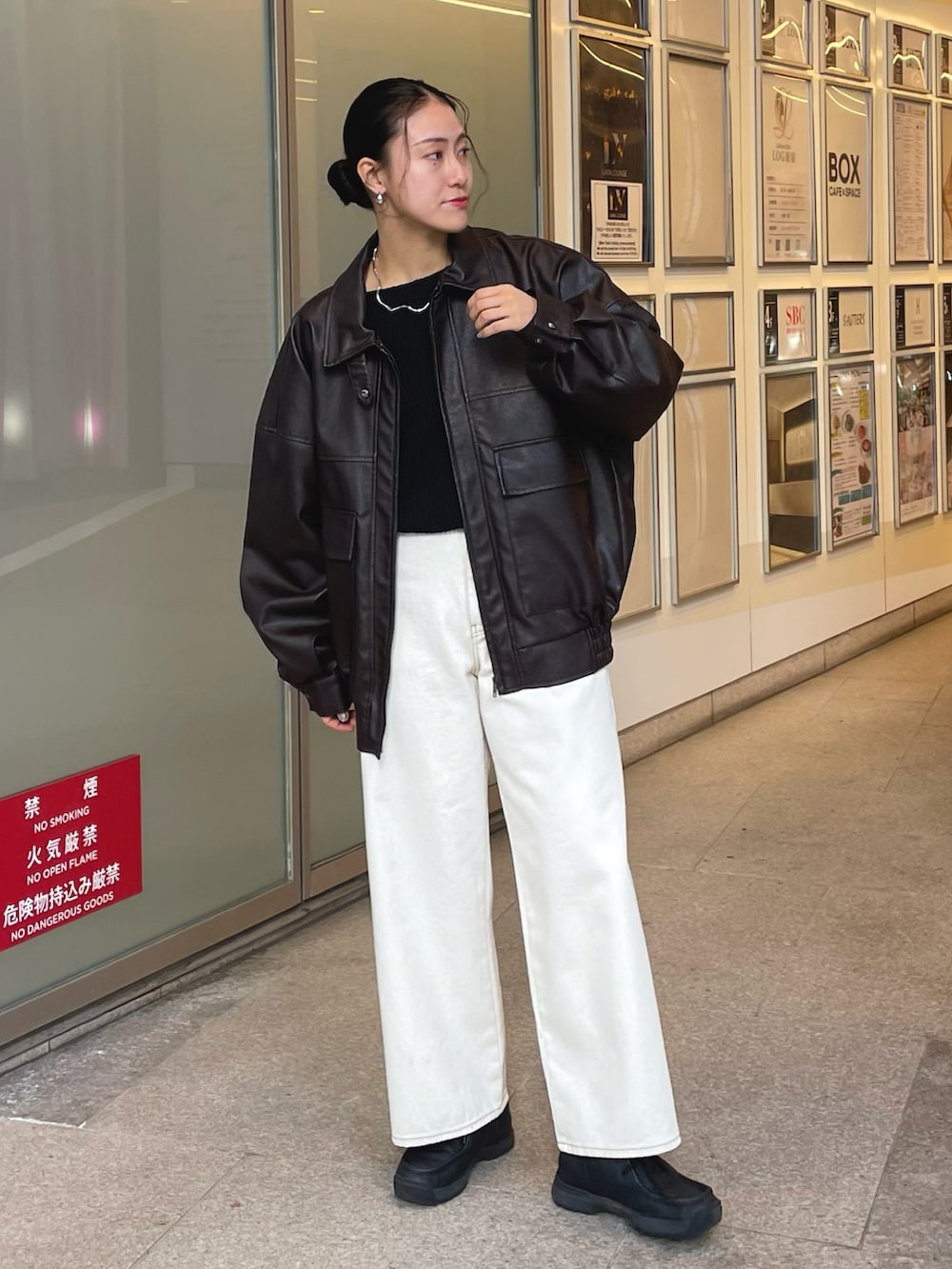 ブラック系のニット/セーター、ホワイト系のデニムパンツ、ブラウン系のブルゾンを着用したレディースの冬コーディネートの2枚目の写真