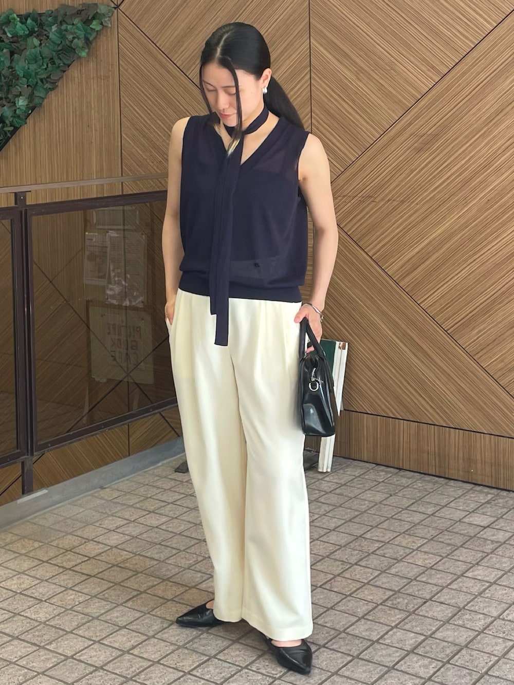 ホワイト系のスラックス、ブルー系のベスト、ブラック系のボストンバッグを着用したレディースの夏コーディネートの3枚目の写真