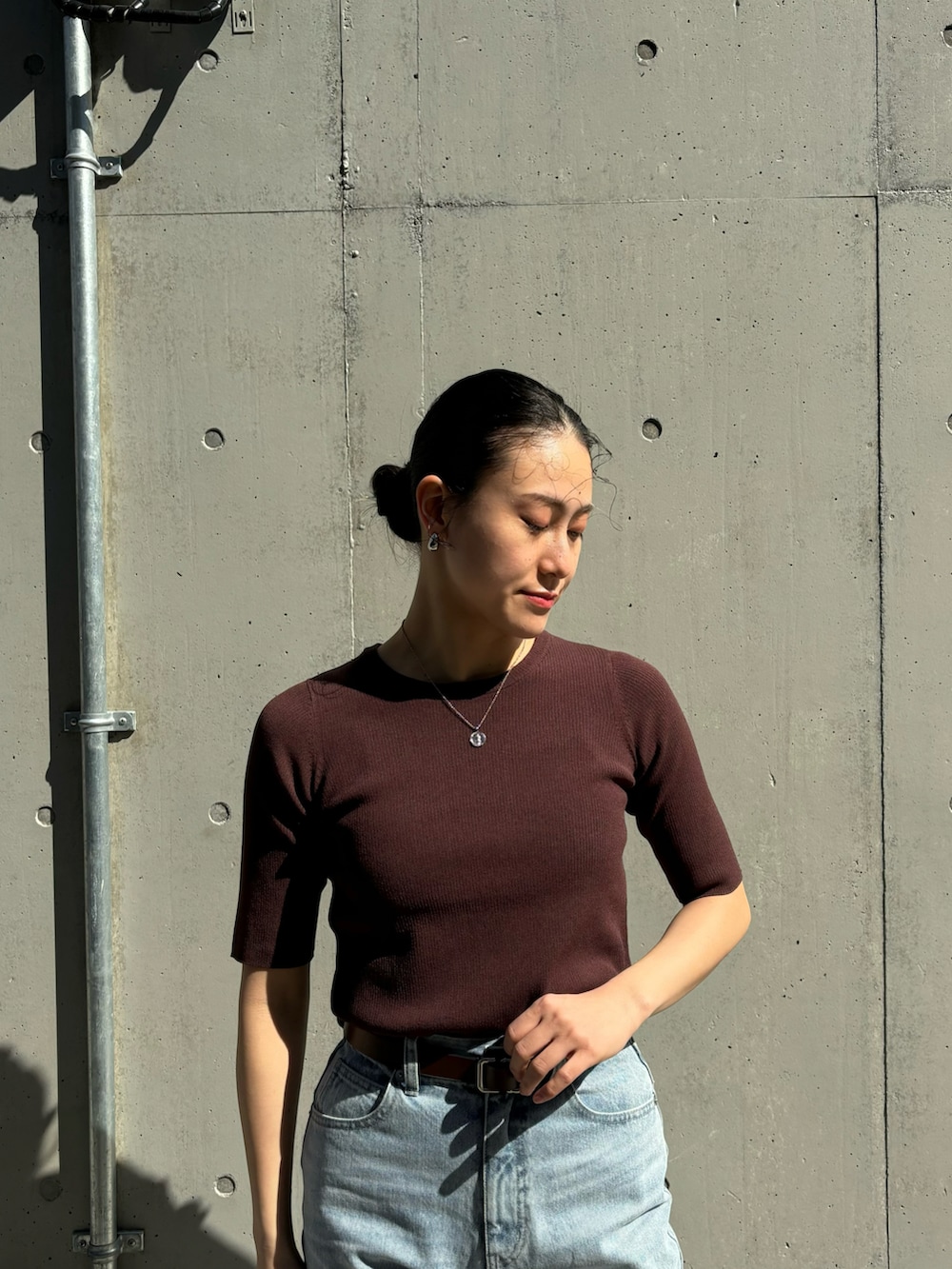 ブラウン系のニット/セーター、ブルー系のデニムパンツ、ホワイト系のハンドバッグを着用したレディースの春コーディネートの3枚目の写真