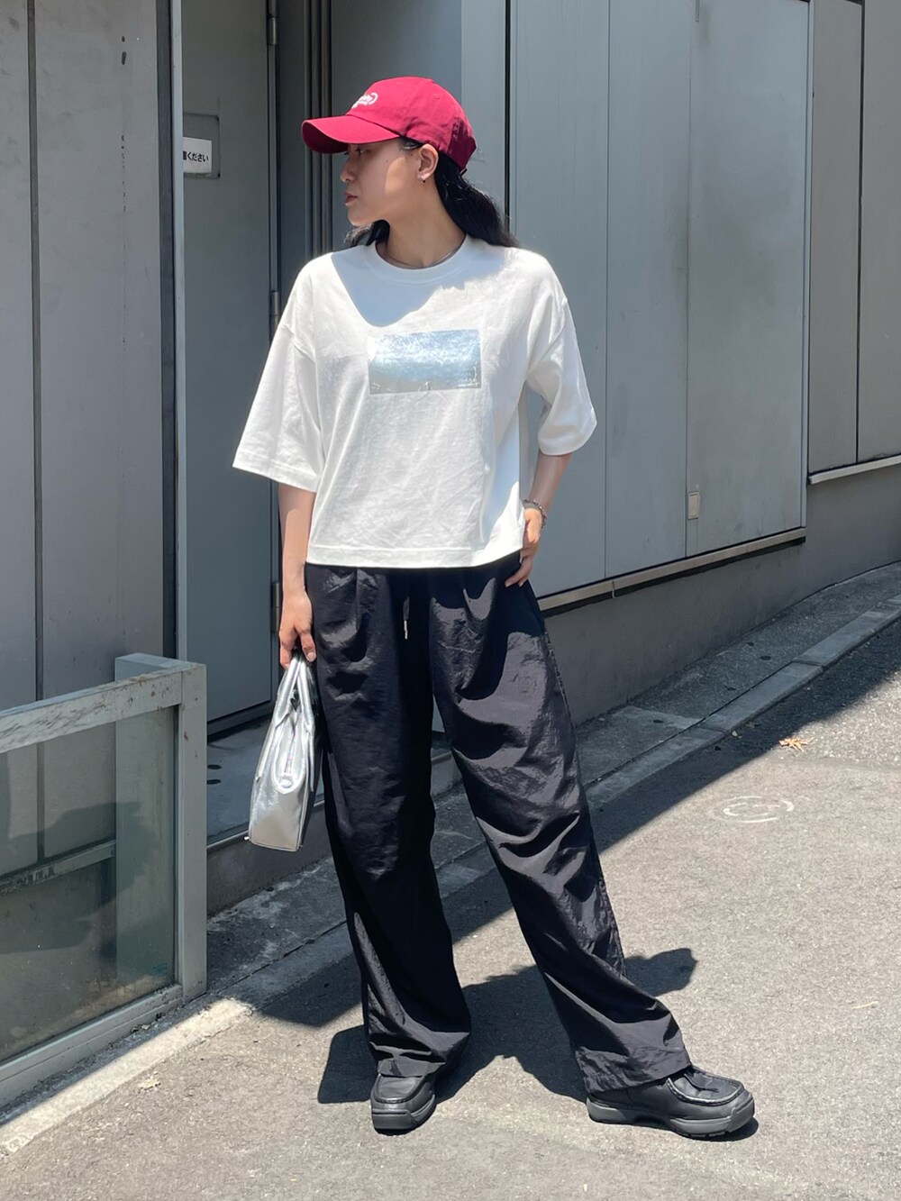 ホワイト系のTシャツ/カットソー、ブラック系のその他パンツ、シルバー系のボストンバッグを着用したレディースの夏コーディネートの2枚目の写真