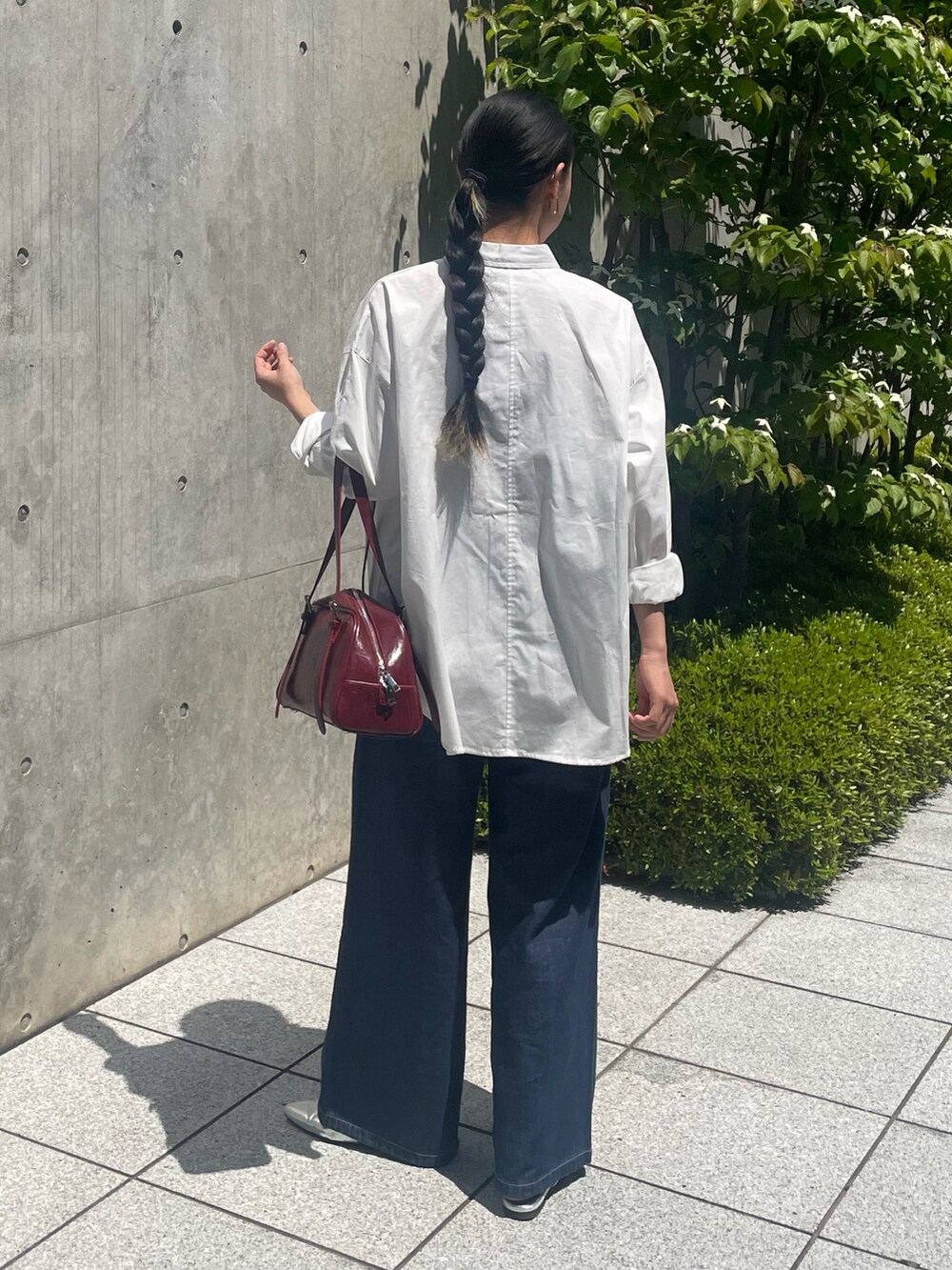 ブルー系のデニムパンツ、ホワイト系のシャツ/ブラウス、レッド系のボストンバッグを着用したレディースの春コーディネートの2枚目の写真