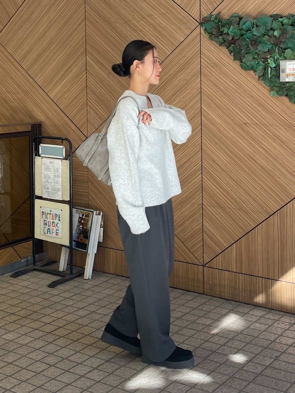 グレー系のニット/セーター、グレー系のボストンバッグ、グレー系のスラックスを着用したレディースの冬コーディネートの2枚目の写真