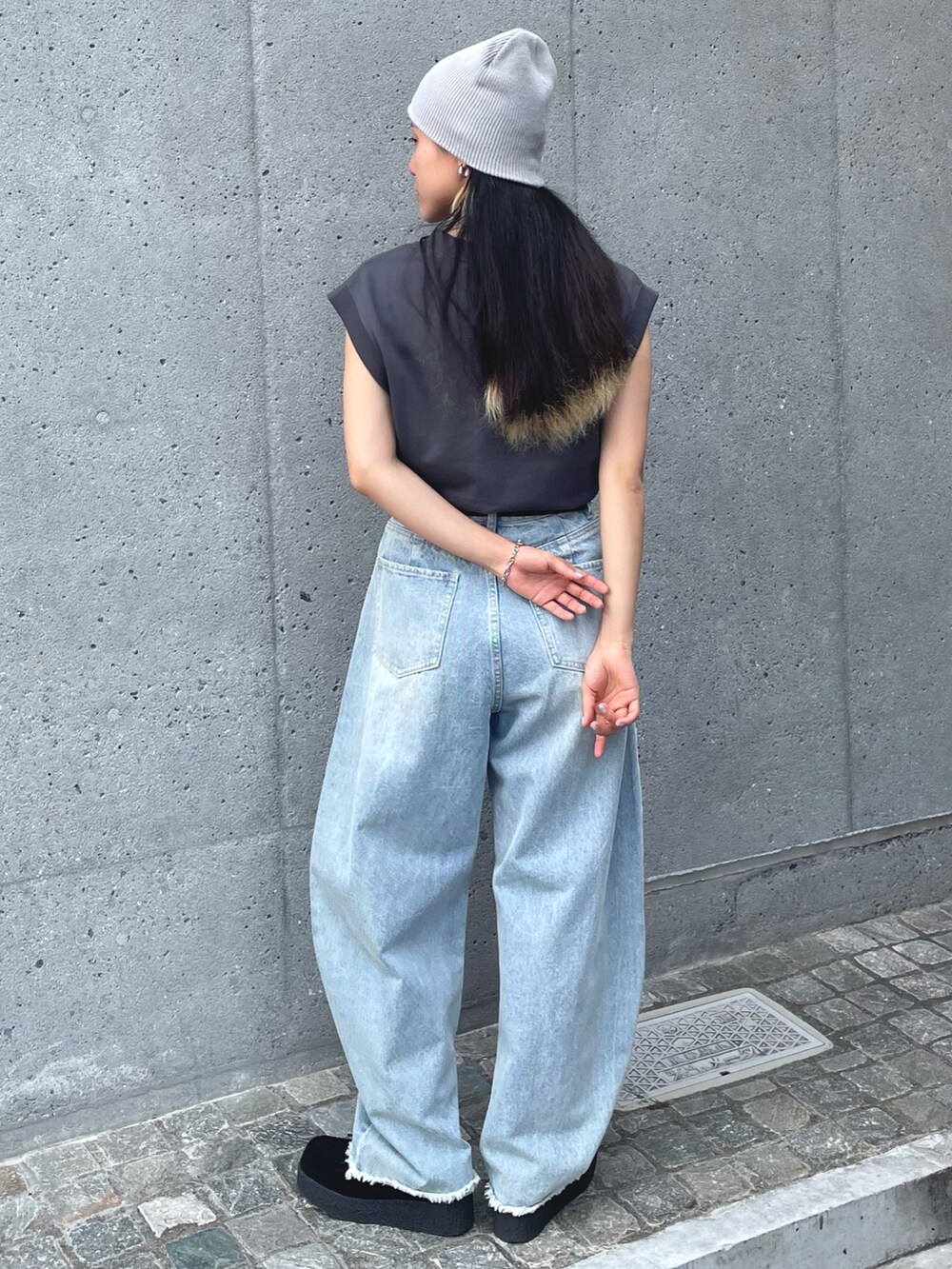 グレー系のベスト、ブルー系のデニムパンツ、ブラック系のモカシン/デッキシューズを着用したレディースの夏コーディネートの2枚目の写真