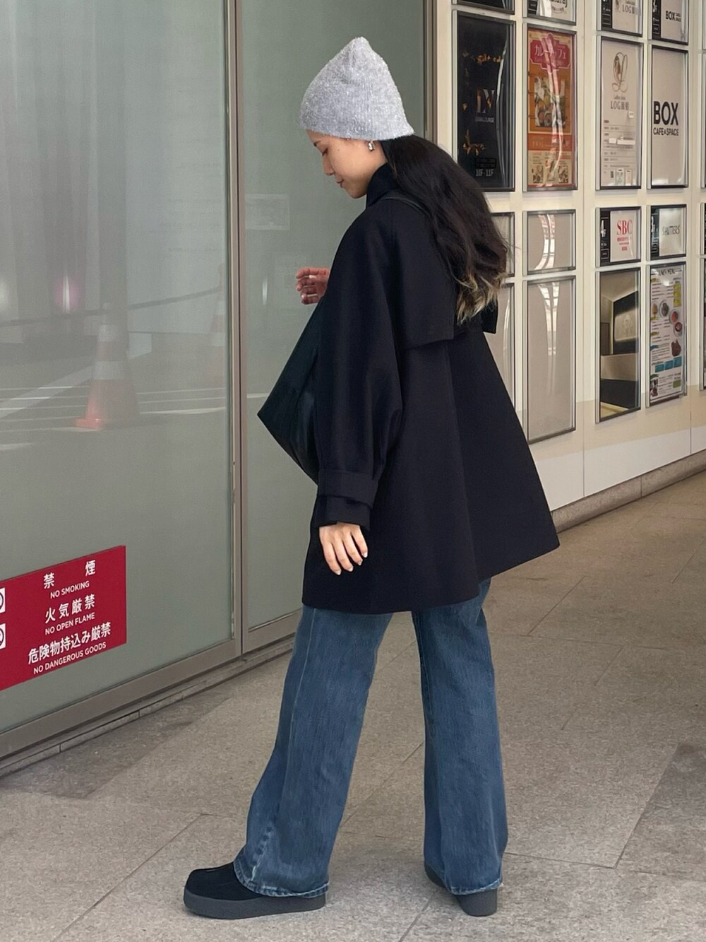 ブラック系のショルダーバッグ、ブルー系のデニムパンツ、ブラック系のモカシン/デッキシューズを着用したレディースの秋コーディネートの3枚目の写真