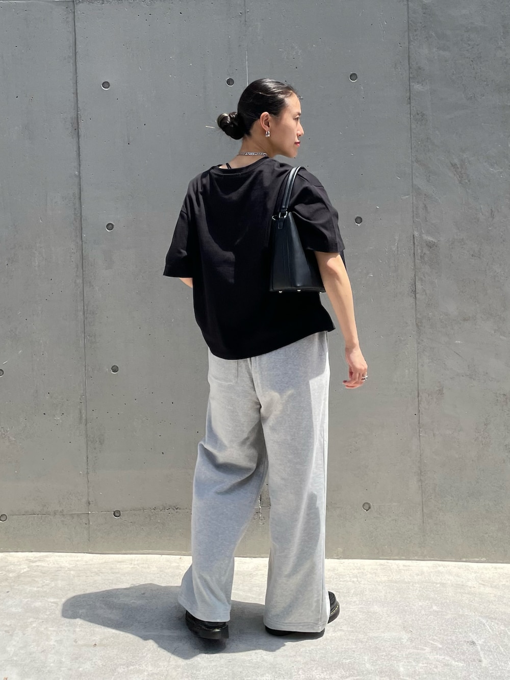 ブラック系のTシャツ/カットソー、グレー系のスウェットパンツ、ブラック系のハンドバッグを着用したレディースの春コーディネートの2枚目の写真