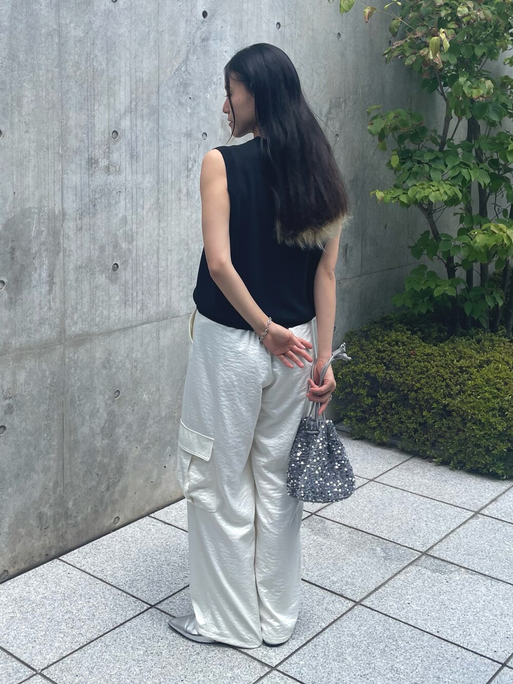 シルバー系のショルダーバッグ、ホワイト系のカーゴパンツ、ブラック系のベストを着用したレディースの夏コーディネートの2枚目の写真