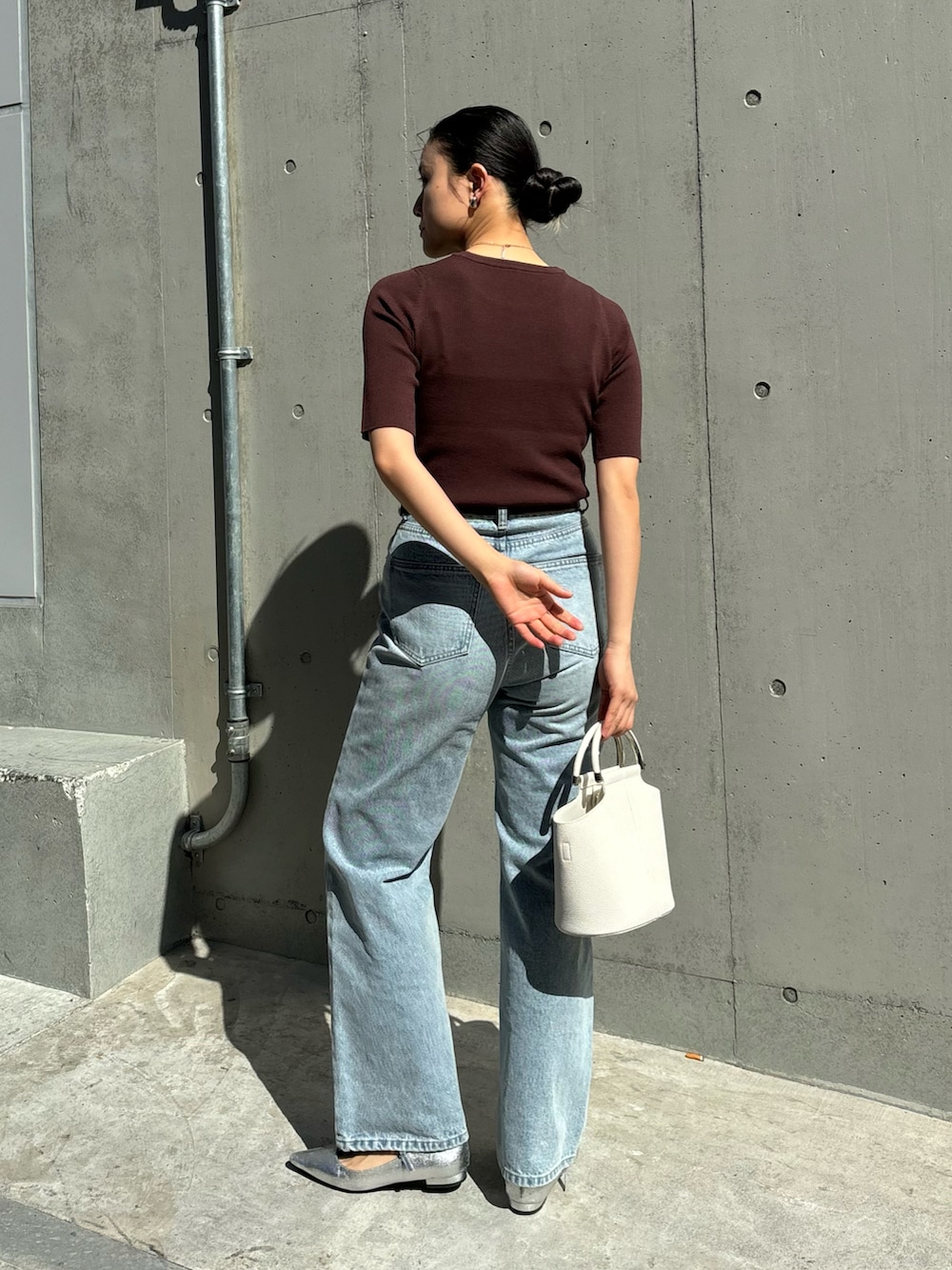 ブラウン系のニット/セーター、ブルー系のデニムパンツ、ホワイト系のハンドバッグを着用したレディースの春コーディネートの2枚目の写真