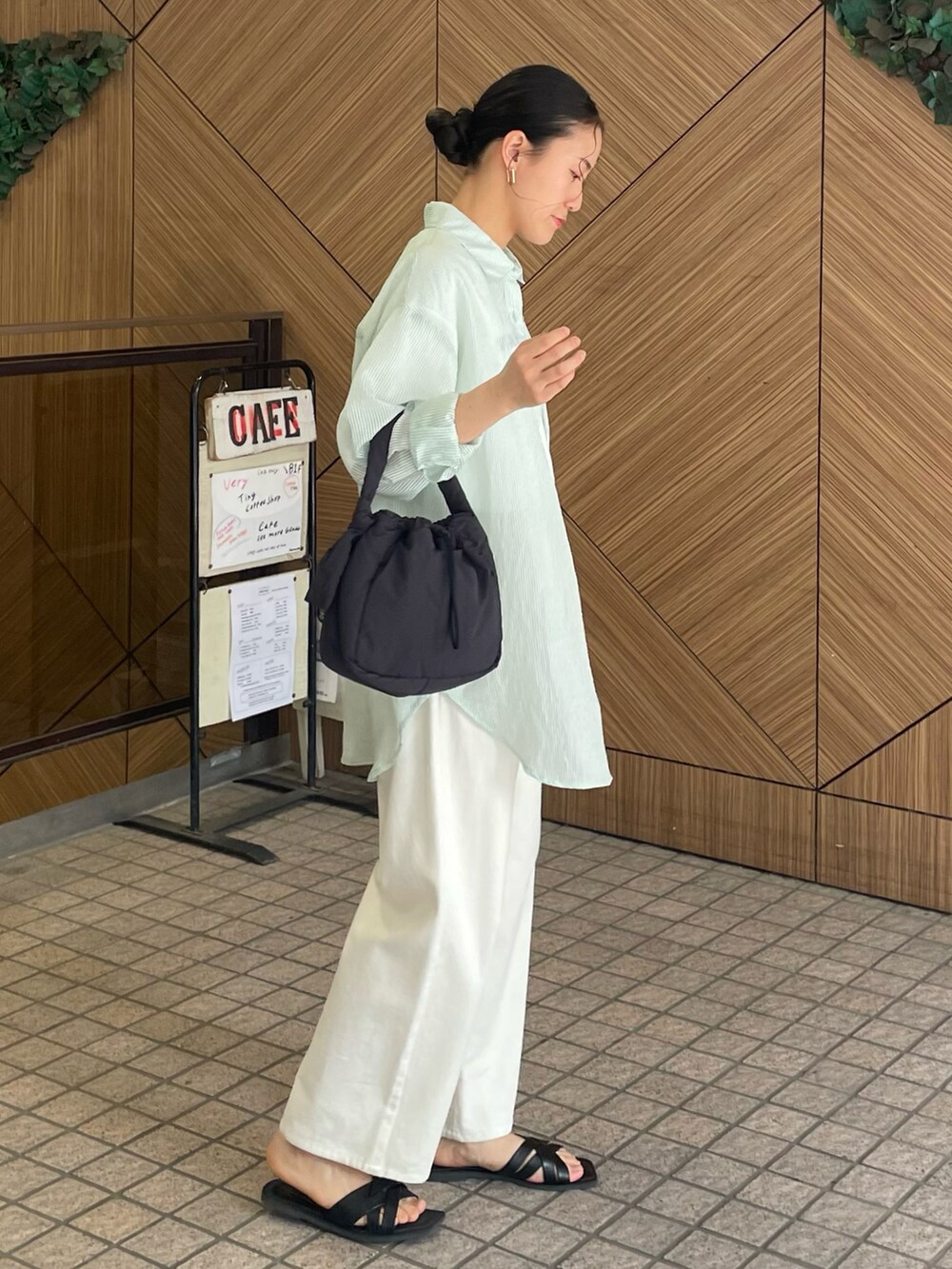 グリーン系のシャツ/ブラウス、ブラック系のハンドバッグ、ブラック系のサンダルを着用したレディースの春コーディネートの2枚目の写真