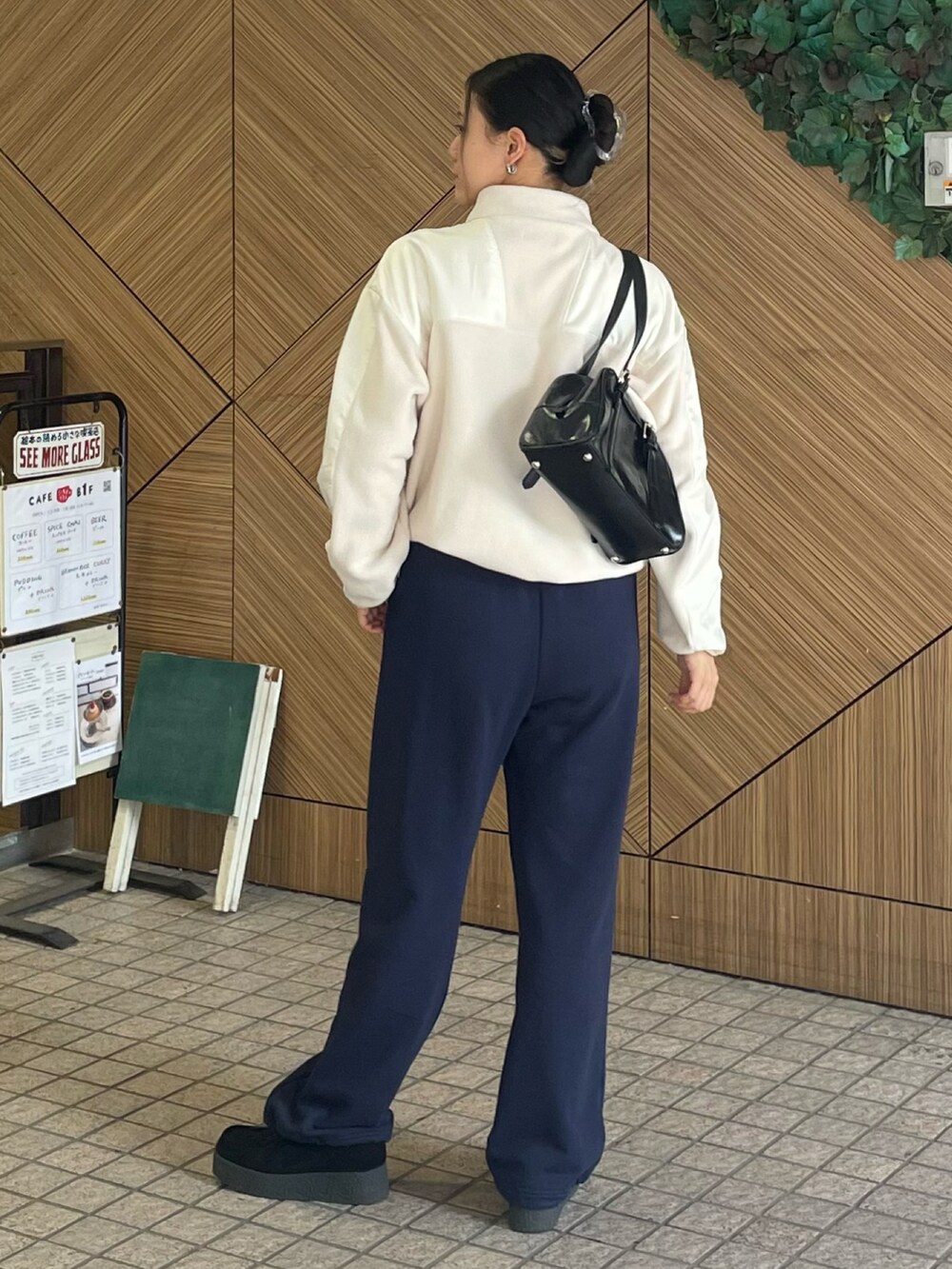 ホワイト系のブルゾン、ブラック系のボストンバッグ、ブラック系のモカシン/デッキシューズを着用したレディースの秋コーディネートの2枚目の写真