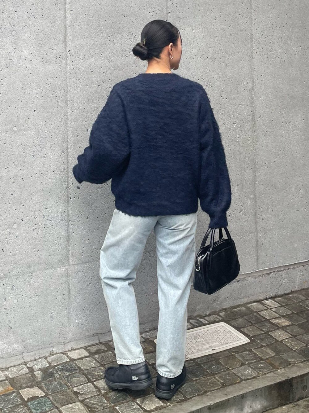 ブルー系のデニムパンツ、ブラック系のボストンバッグ、ブルー系のカーディガン/ボレロを着用したレディースの冬コーディネートの2枚目の写真