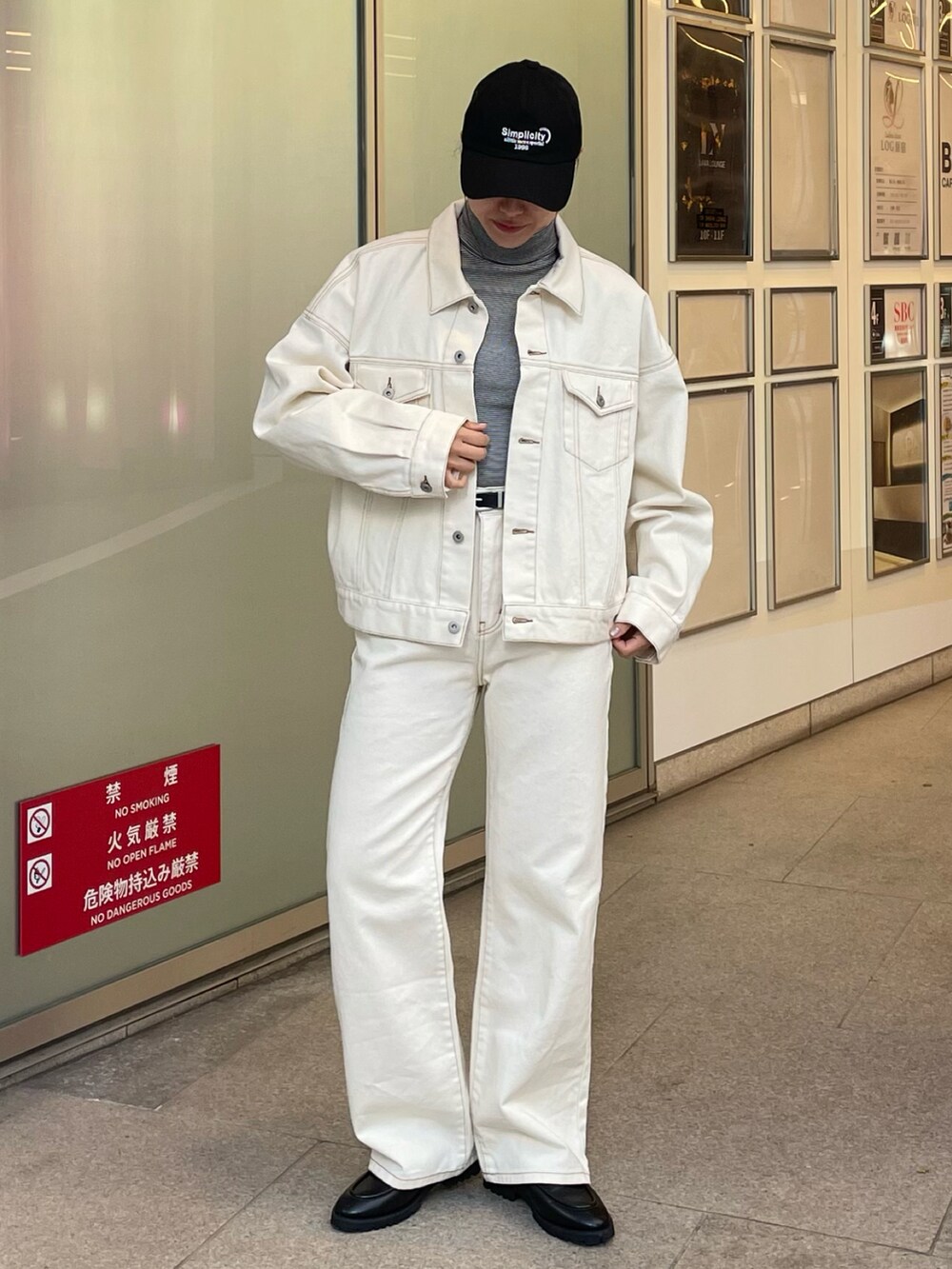 ホワイト系のデニムジャケット、ホワイト系のデニムパンツ、ブラック系のキャップを着用したレディースの冬コーディネートの2枚目の写真