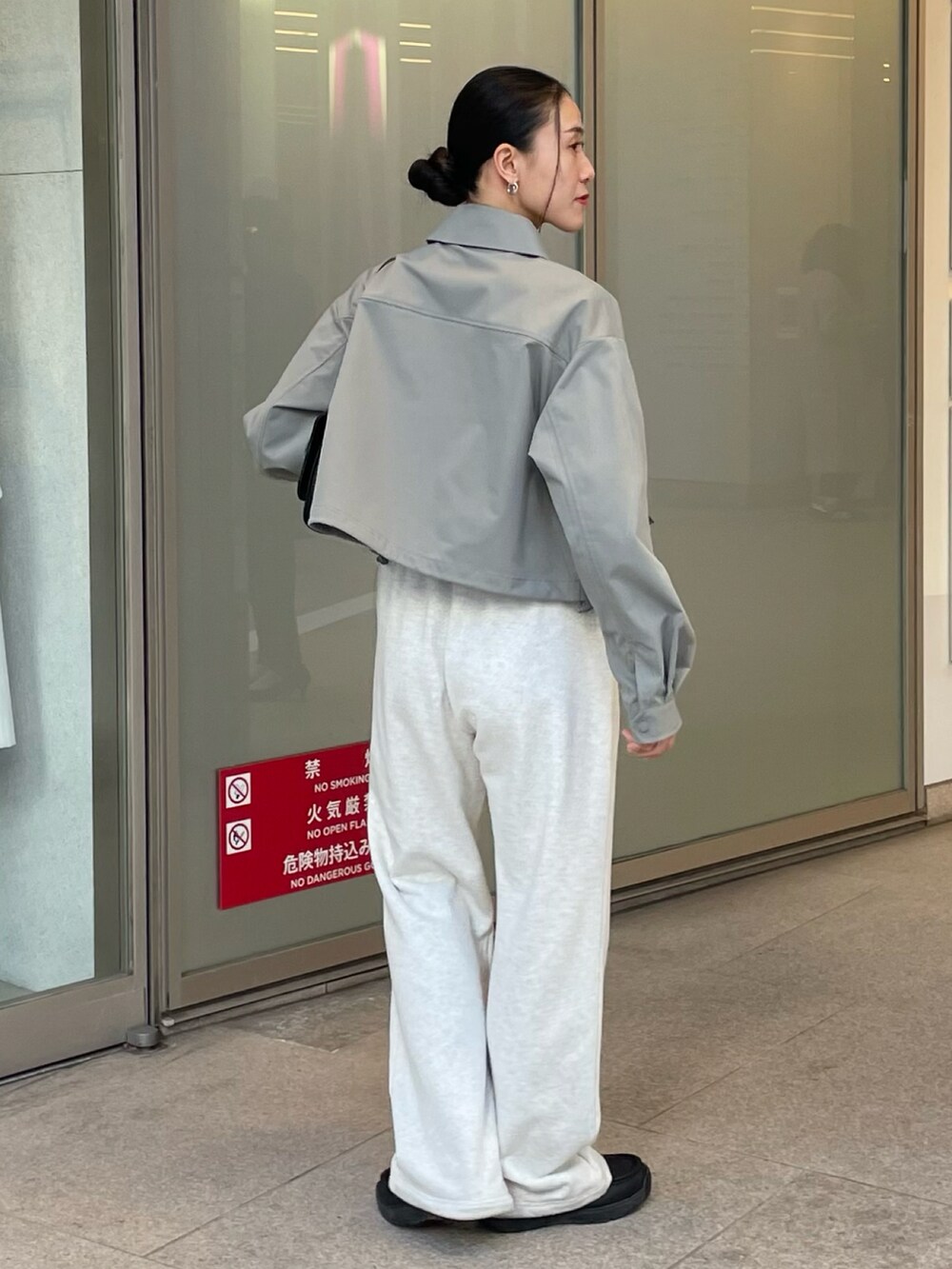 ブラック系のハンドバッグ、ホワイト系のスウェットパンツ、グリーン系のブルゾンを着用したレディースの冬コーディネートの3枚目の写真