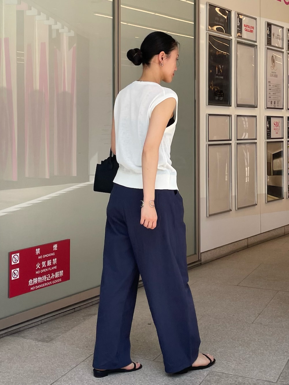 ブルー系のその他パンツ、ブラック系のハンドバッグ、ホワイト系のベストを着用したレディースの春コーディネートの2枚目の写真