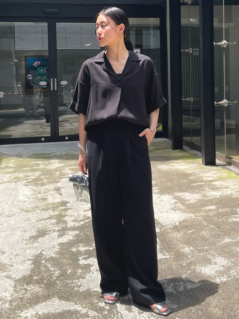ブラック系のシャツ/ブラウス、ブラック系のスラックス、シルバー系のサンダルを着用したレディースの夏コーディネートの2枚目の写真