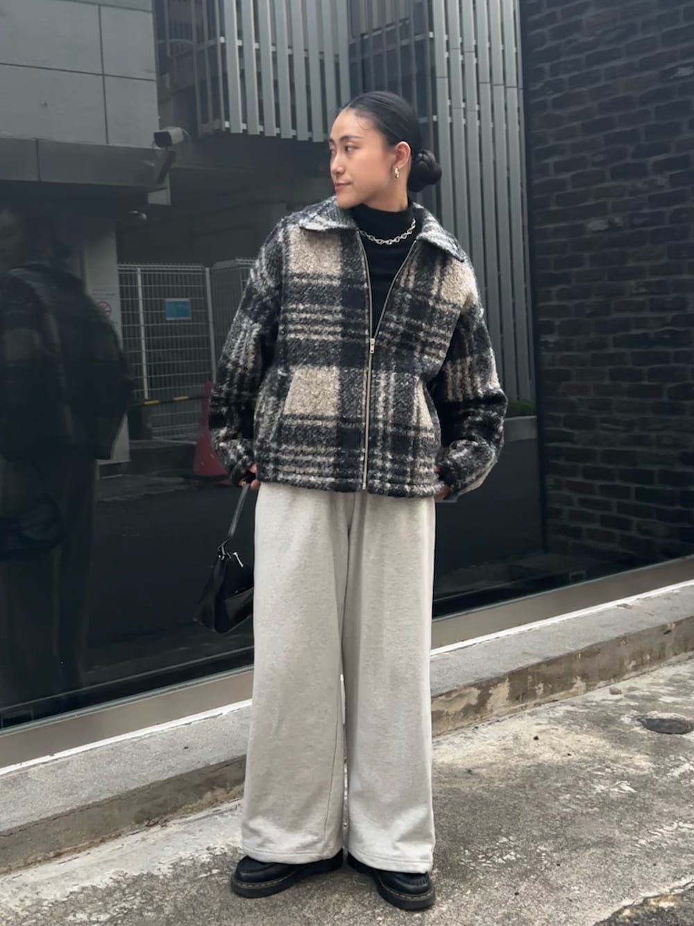 ブラック系のブルゾン、グレー系のスウェットパンツ、ブラック系のハンドバッグを着用したレディースの春コーディネートの2枚目の写真