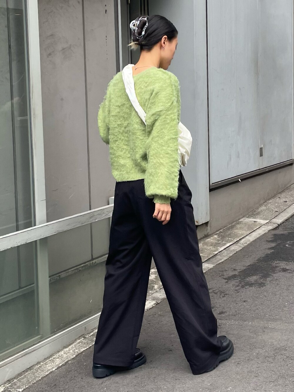 グリーン系のニット/セーター、ブラック系のその他パンツ、ホワイト系のショルダーバッグを着用したレディースの秋コーディネートの2枚目の写真