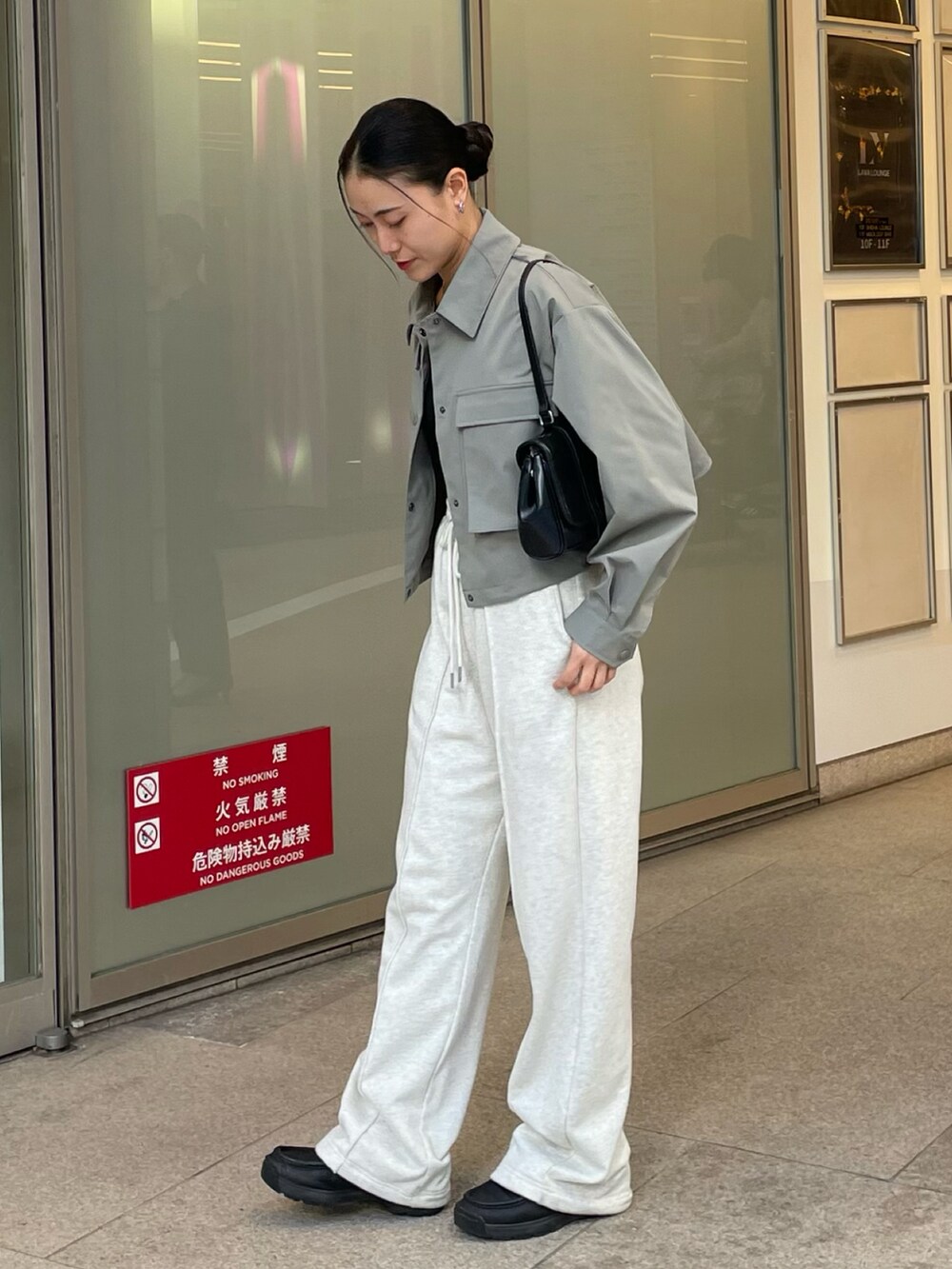 ブラック系のハンドバッグ、ホワイト系のスウェットパンツ、グリーン系のブルゾンを着用したレディースの冬コーディネートの2枚目の写真