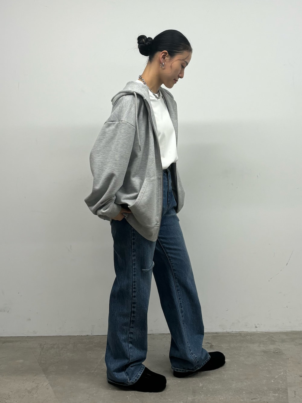 グレー系のパーカー、ブルー系のデニムパンツを着用したレディースの秋コーディネートの2枚目の写真