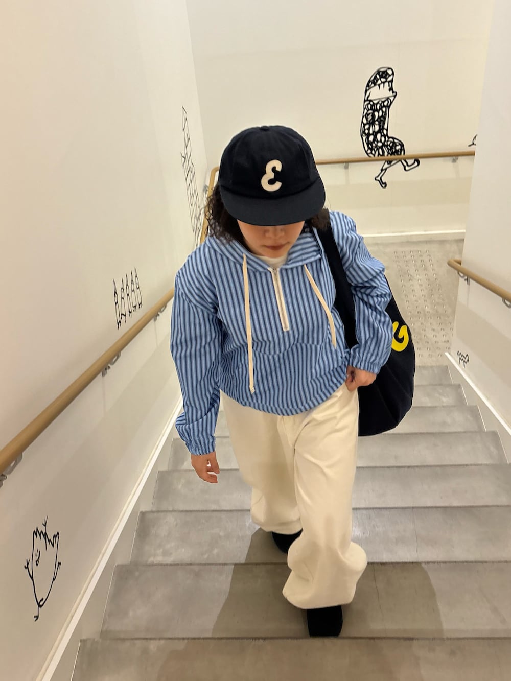 ブルー系のバッグ、ブルー系のトップス、ホワイト系のパンツを着用したレディースの春コーディネートの2枚目の写真