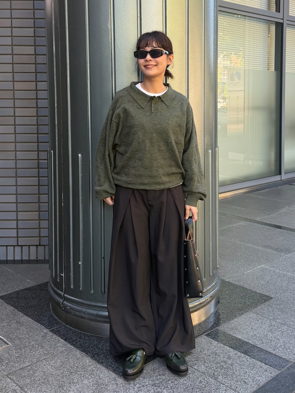 グリーン系のニット/セーター、ブラック系のパンツ、ブラック系のハンドバッグを着用したレディースの秋コーディネートの2枚目の写真