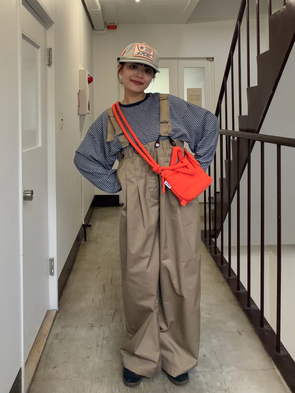 ベージュ系のチノパンツ、ブルー系のTシャツ/カットソー、オレンジ系のハンドバッグを着用したレディースの秋コーディネートの2枚目の写真