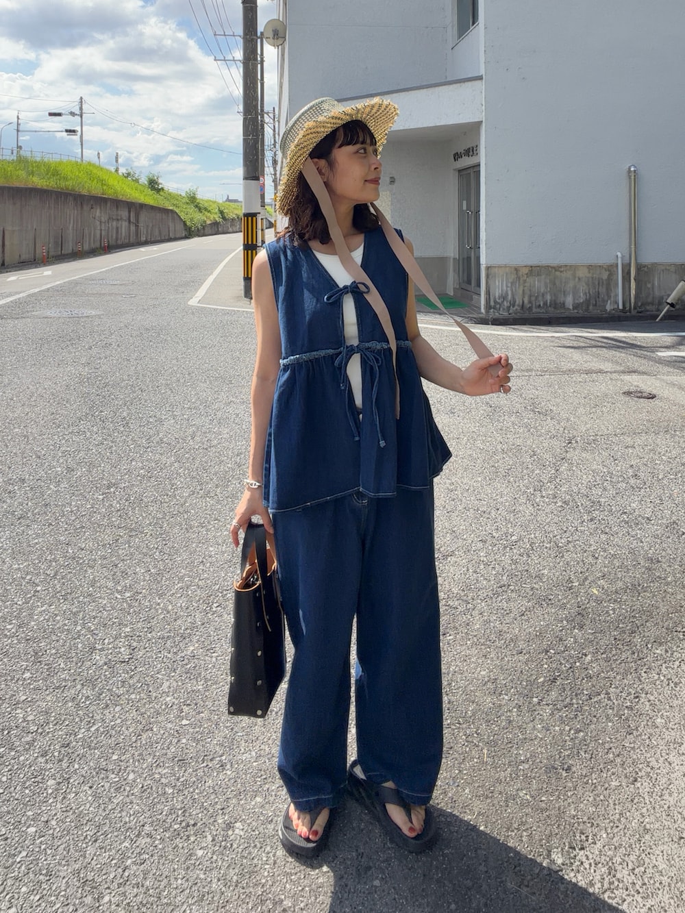 ブルー系のワンピース、ブラック系のハンドバッグ、ブラック系のサンダルを着用したレディースの夏コーディネートの2枚目の写真
