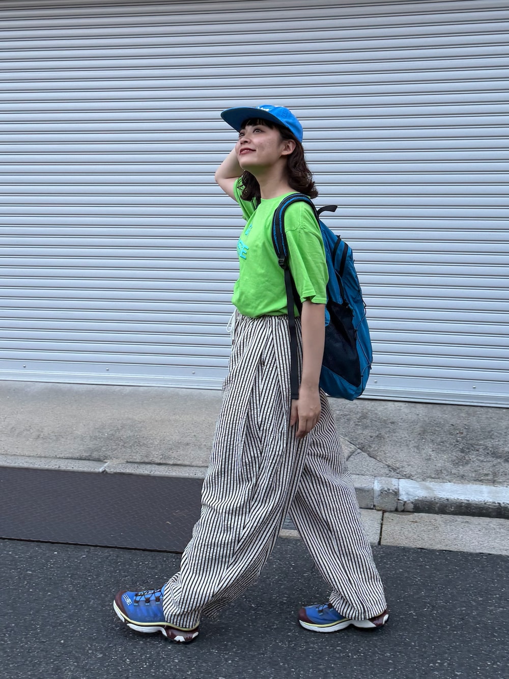グリーン系のトップス、ホワイト系のパンツ、ブルー系のシューズを着用したレディースの夏コーディネートの2枚目の写真