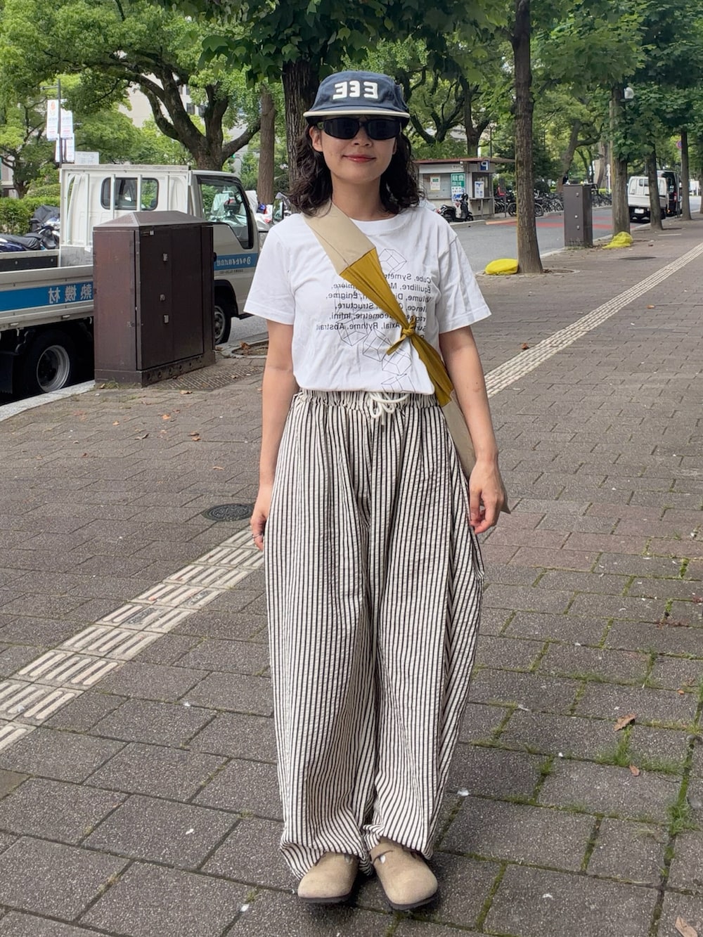 イエロー系のバッグ、ホワイト系のパンツ、ベージュ系のサンダルを着用したレディースの夏コーディネートの2枚目の写真