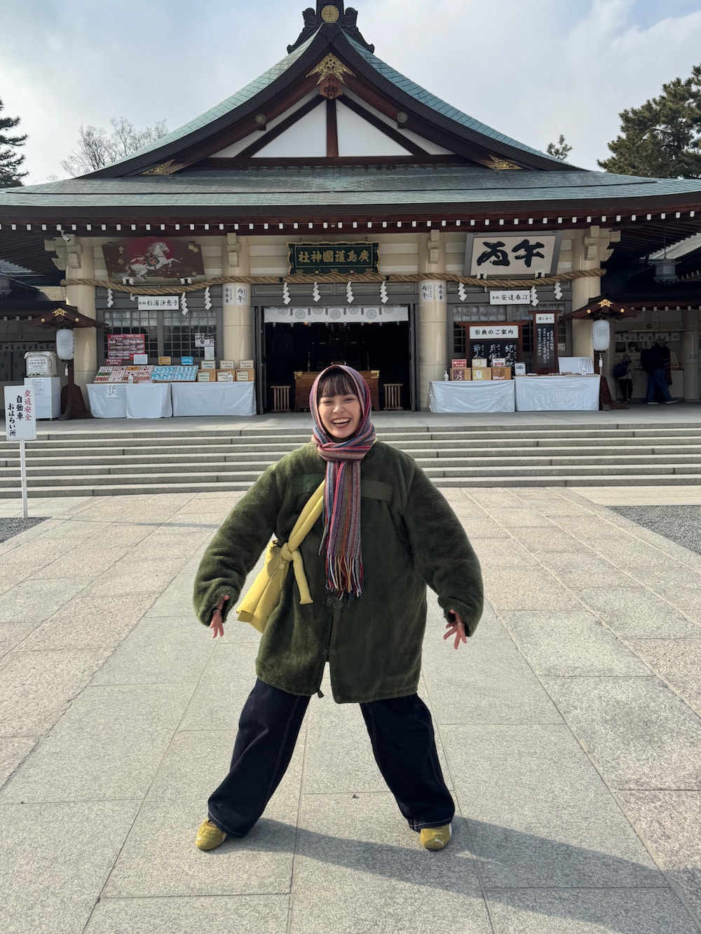 ブルー系のハンドバッグ、グリーン系のジャケット/アウター、ブルー系のデニムパンツを着用したレディースの冬コーディネートの2枚目の写真