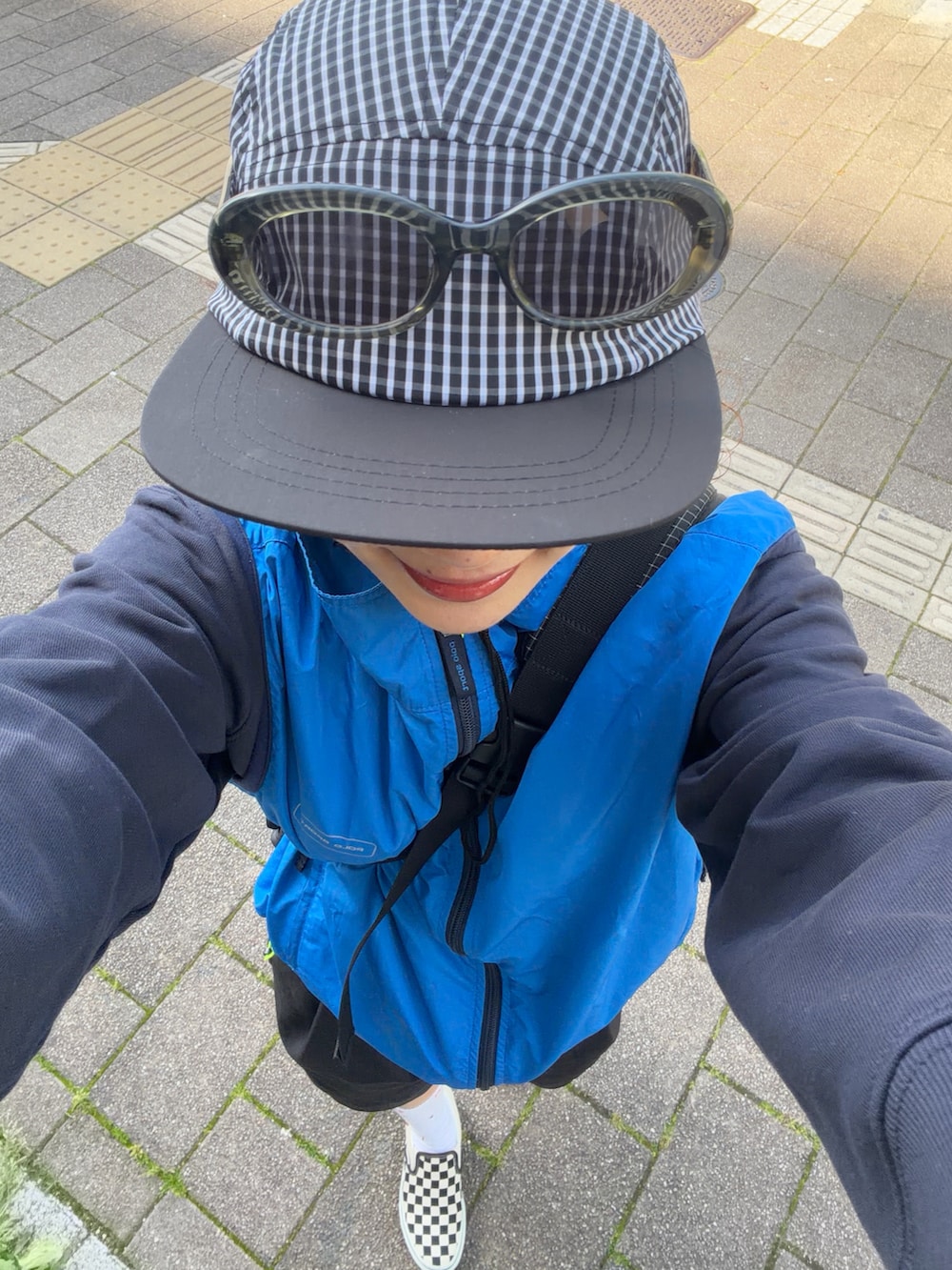 ブルー系のベスト、ブラック系のパンツ、ブラック系のスリッポンを着用したレディースの春コーディネートの3枚目の写真