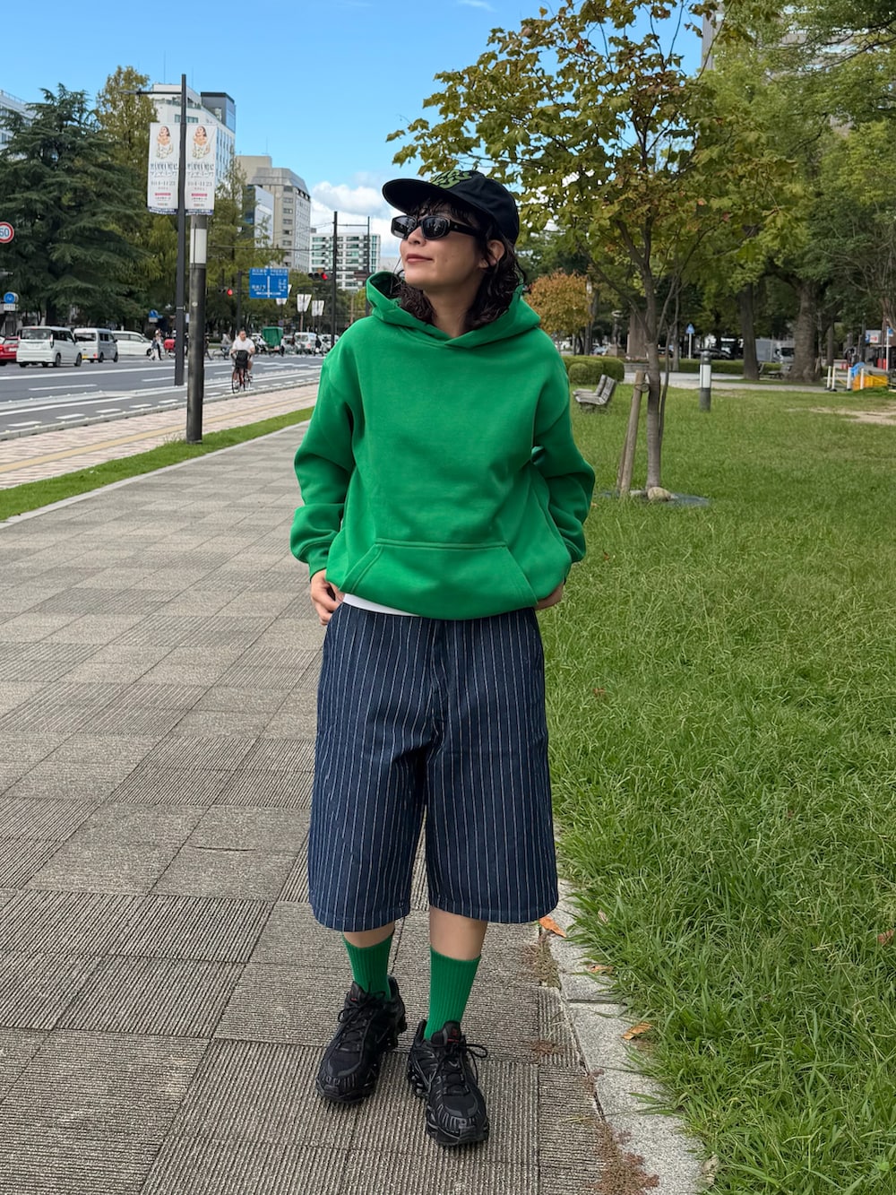 ブラック系のスニーカー、ブルー系のデニムパンツ、グリーン系のトップスを着用したレディースの秋コーディネートの3枚目の写真