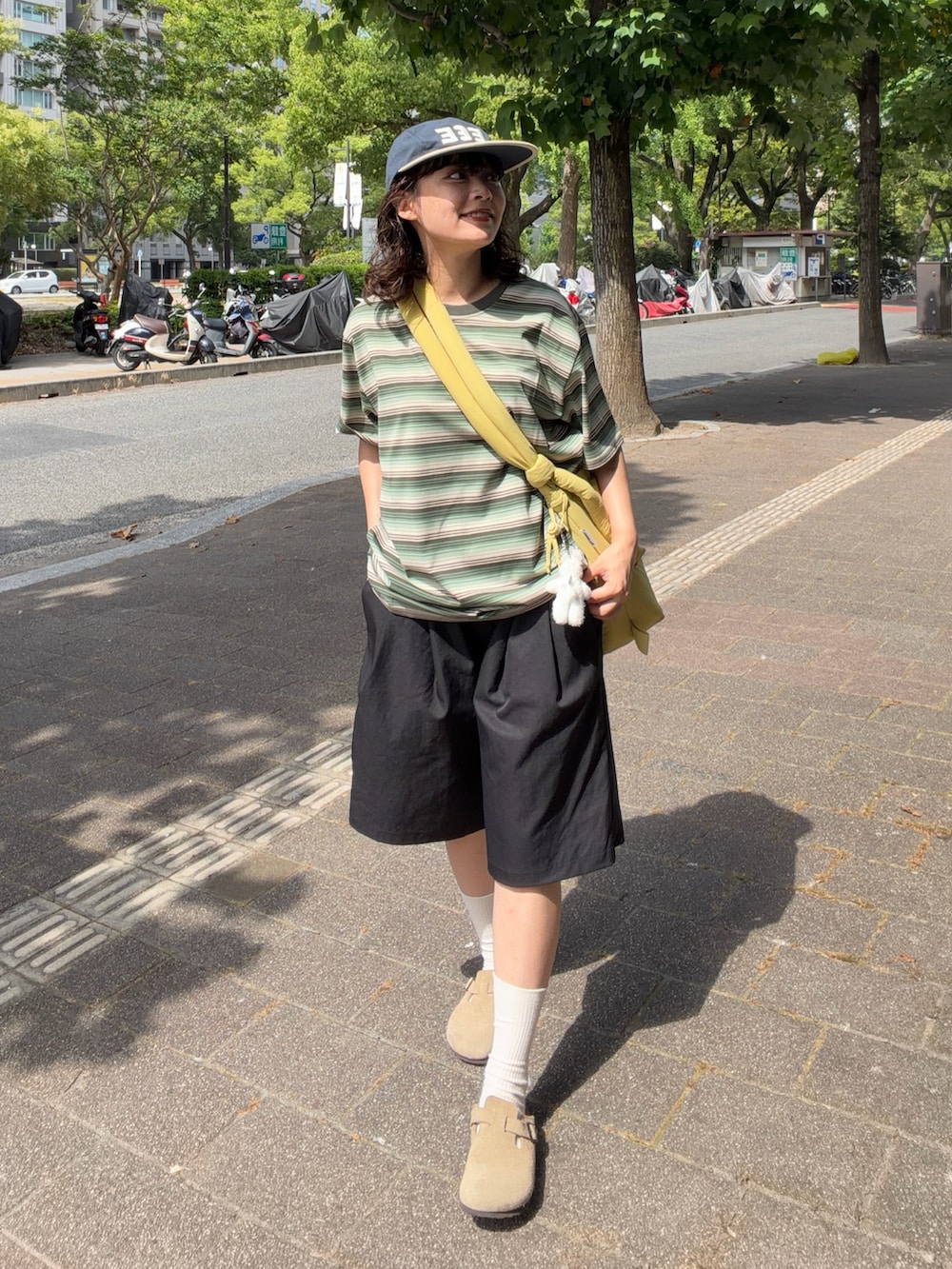 グリーン系のTシャツ/カットソー、イエロー系のハンドバッグ、ベージュ系のサンダルを着用したレディースの夏コーディネートの2枚目の写真
