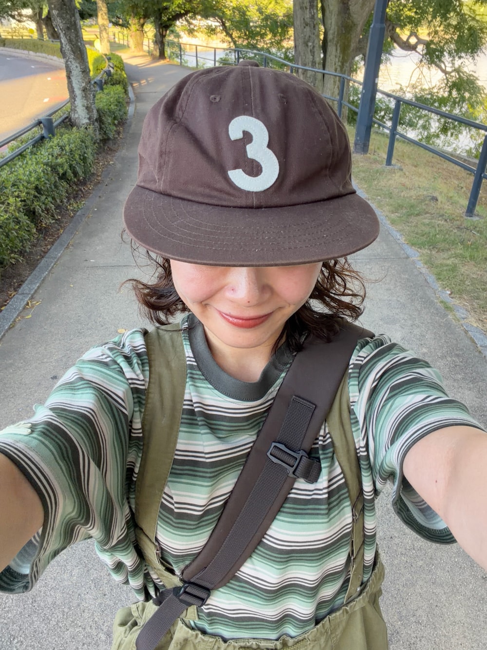 ブラウン系のショルダーバッグ、グリーン系のTシャツ/カットソー、グリーン系のカーゴパンツを着用したレディースの夏コーディネートの3枚目の写真