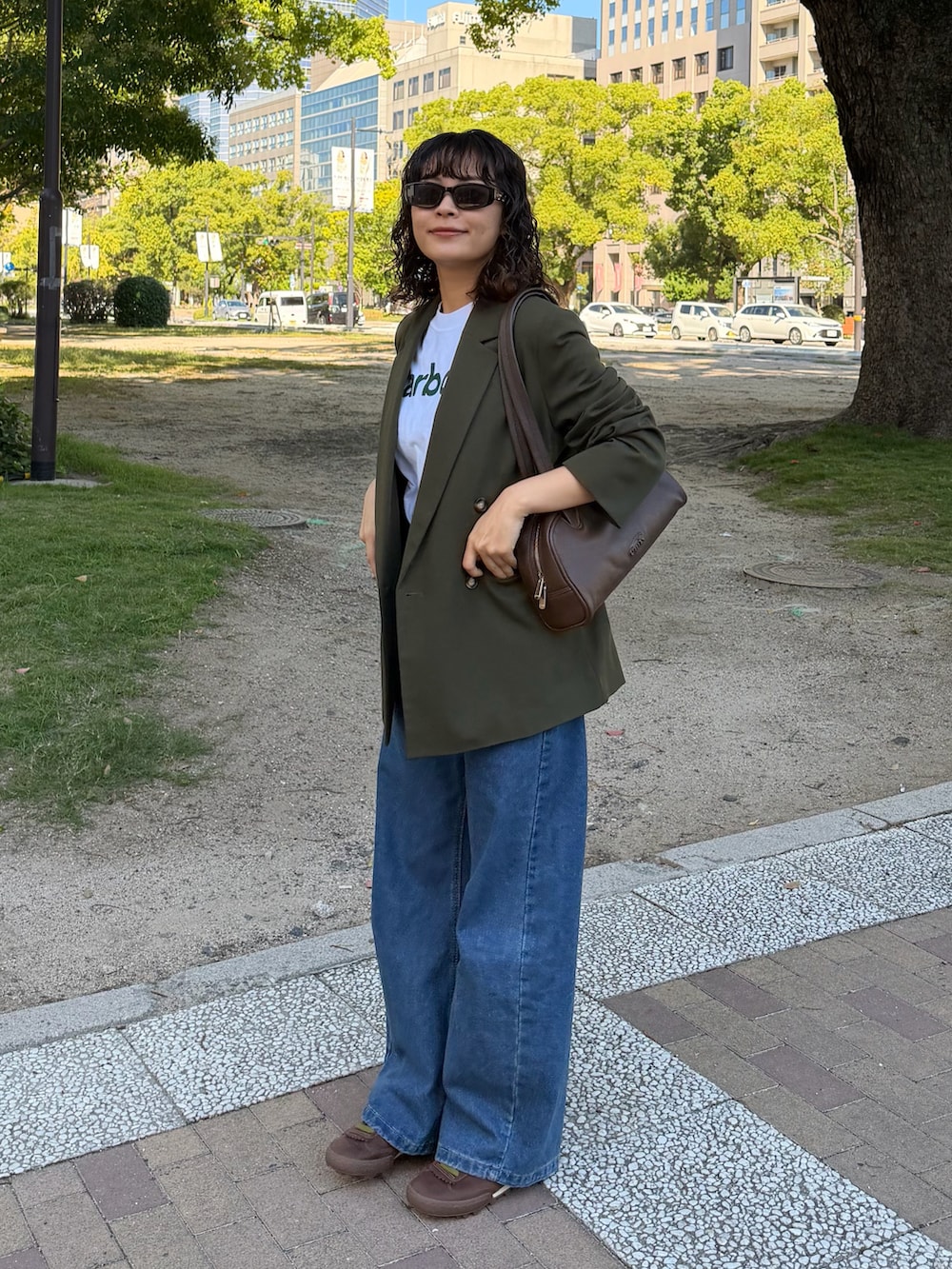 グリーン系のジャケット/アウター、ブラウン系のショルダーバッグ、ホワイト系のTシャツ/カットソーを着用したレディースの秋コーディネートの2枚目の写真