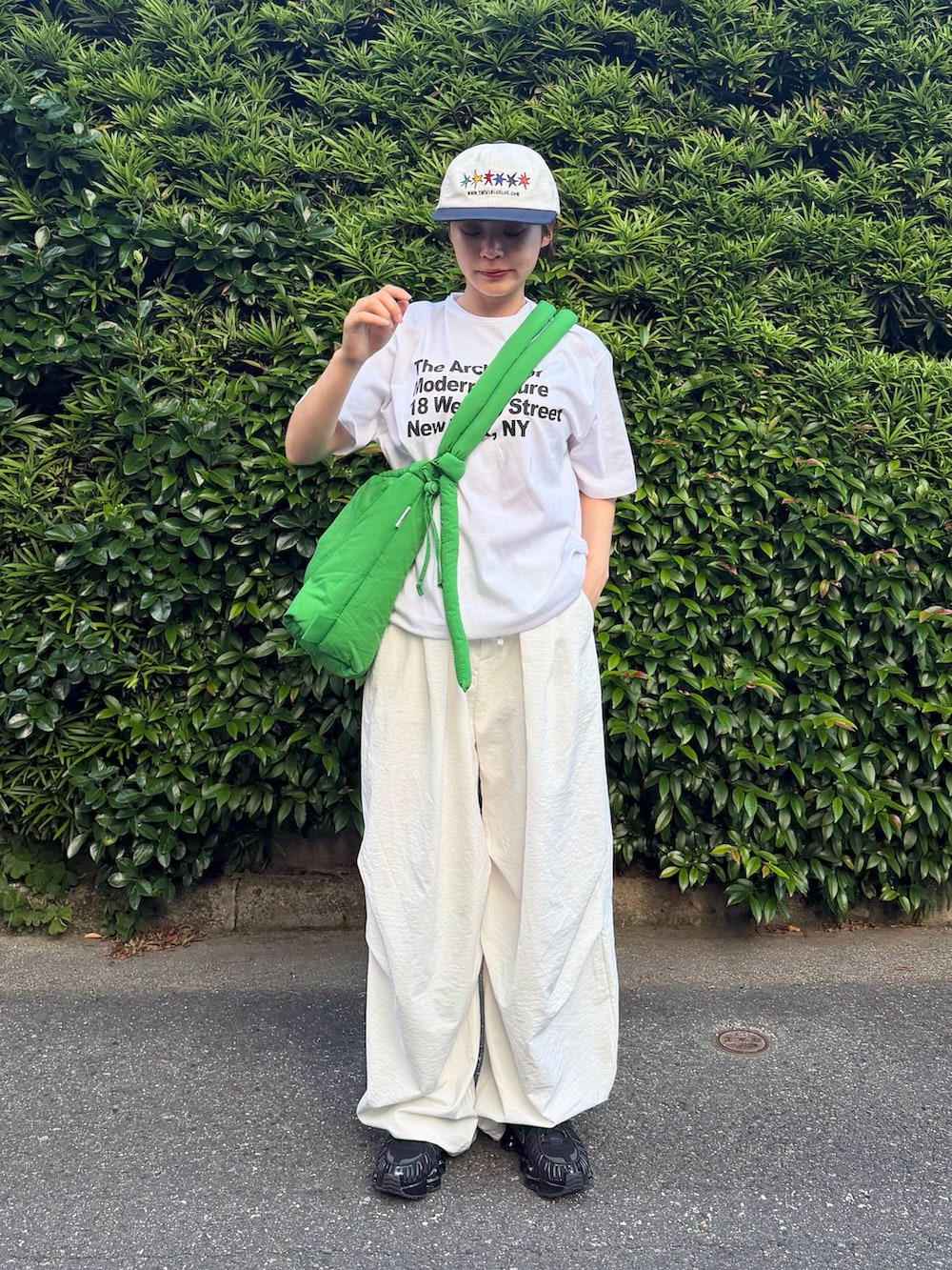 ブラック系のスニーカー、グリーン系のハンドバッグ、ホワイト系のTシャツ/カットソーを着用したレディースの夏コーディネートの2枚目の写真