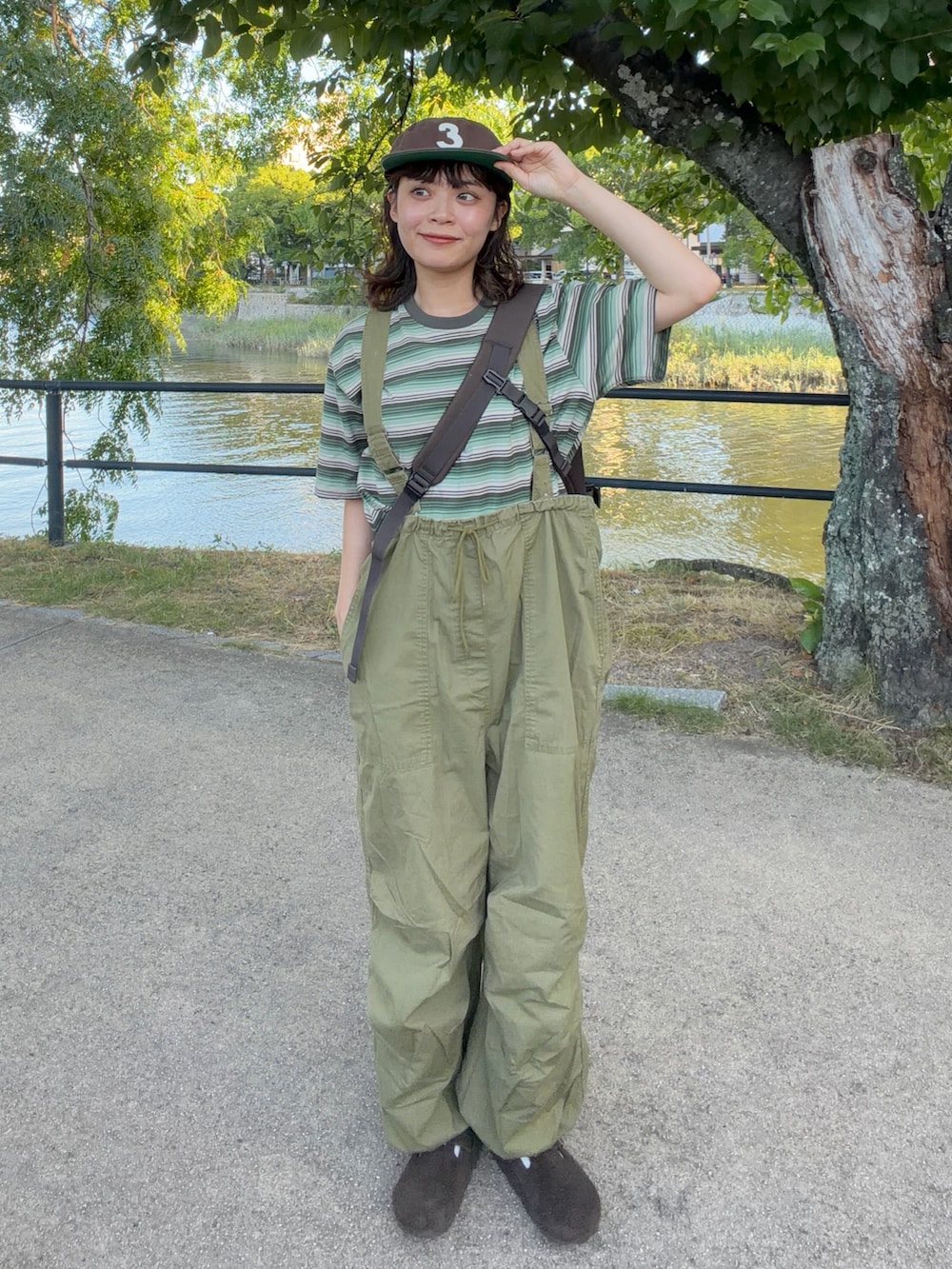 ブラウン系のショルダーバッグ、グリーン系のTシャツ/カットソー、グリーン系のカーゴパンツを着用したレディースの夏コーディネートの2枚目の写真