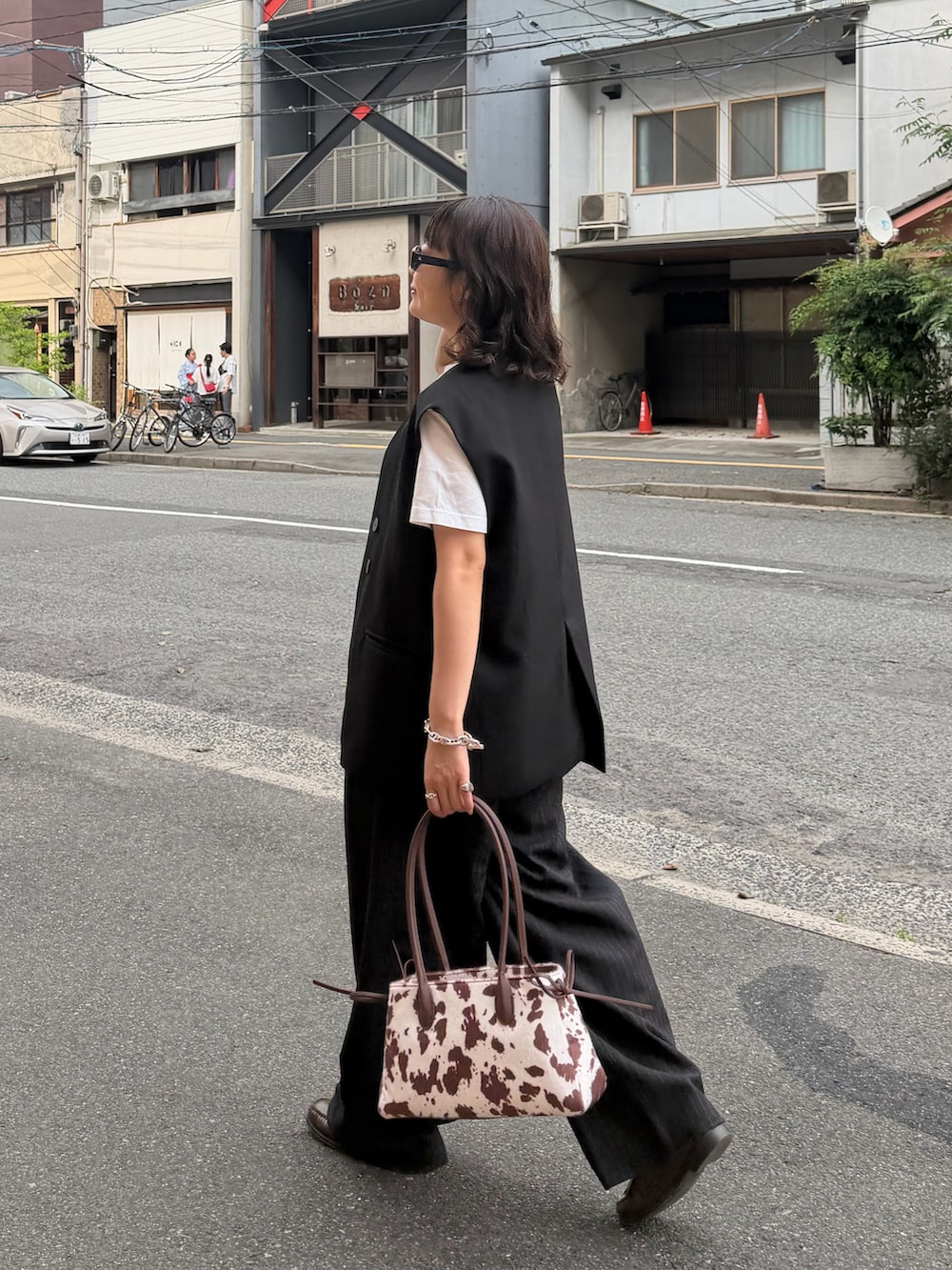 ブラウン系のローファー、ブラウン系のボストンバッグ、ブラック系のパンツを着用したレディースの夏コーディネートの2枚目の写真
