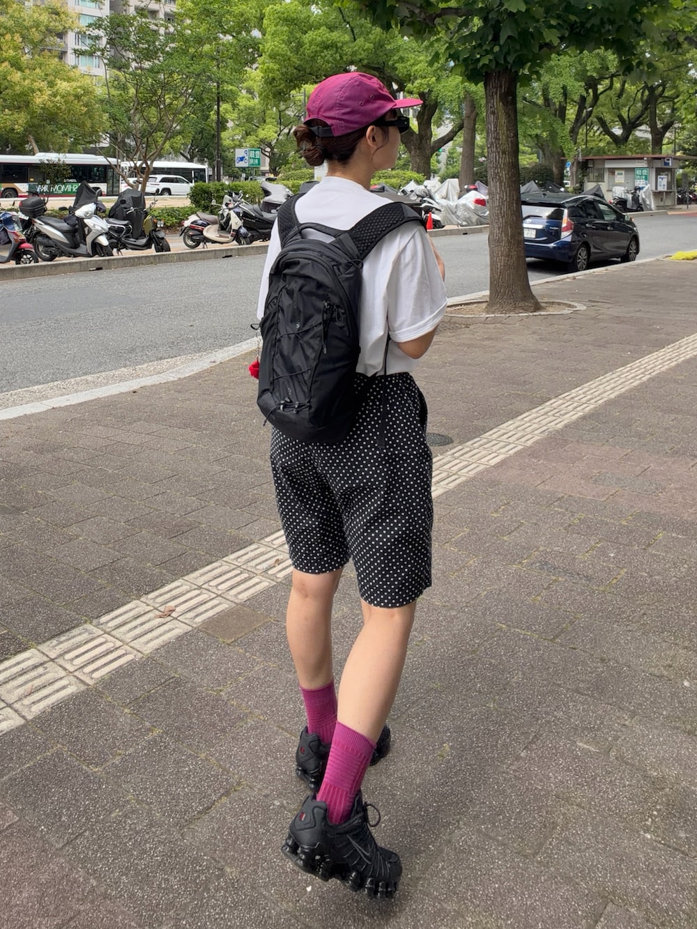 ブラック系のスニーカー、ブラック系のバックパック/リュック、ホワイト系のTシャツ/カットソーを着用したレディースの夏コーディネートの3枚目の写真
