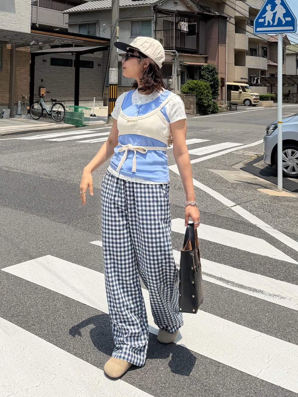 ホワイト系のキャミソール、ブルー系のタンクトップ、ブラック系のハンドバッグを着用したレディースの夏コーディネートの2枚目の写真