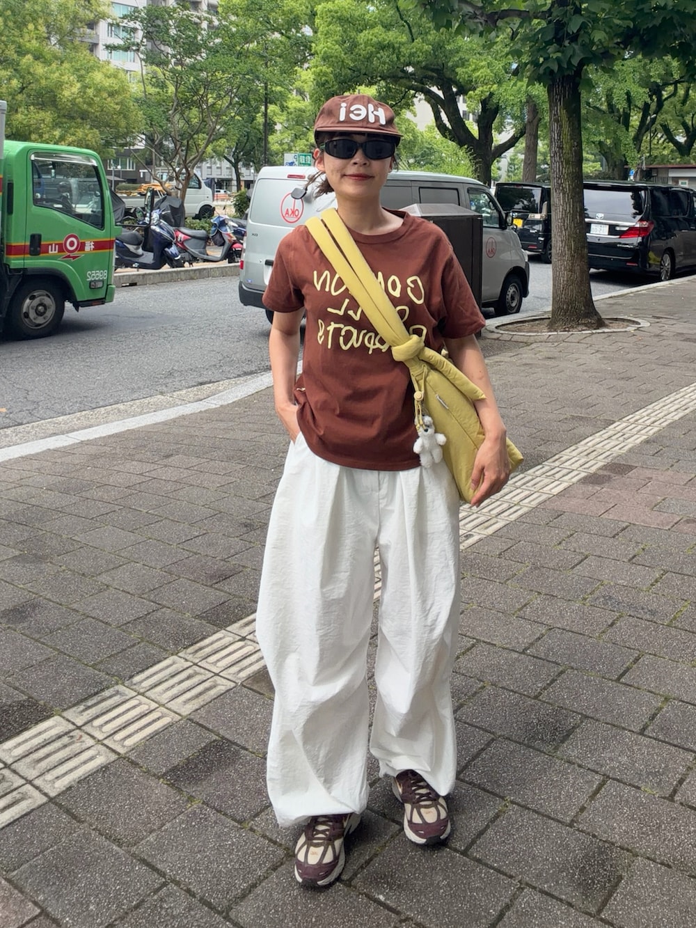 ブラウン系のTシャツ/カットソー、イエロー系のハンドバッグ、ホワイト系のパンツを着用したレディースの夏コーディネートの2枚目の写真