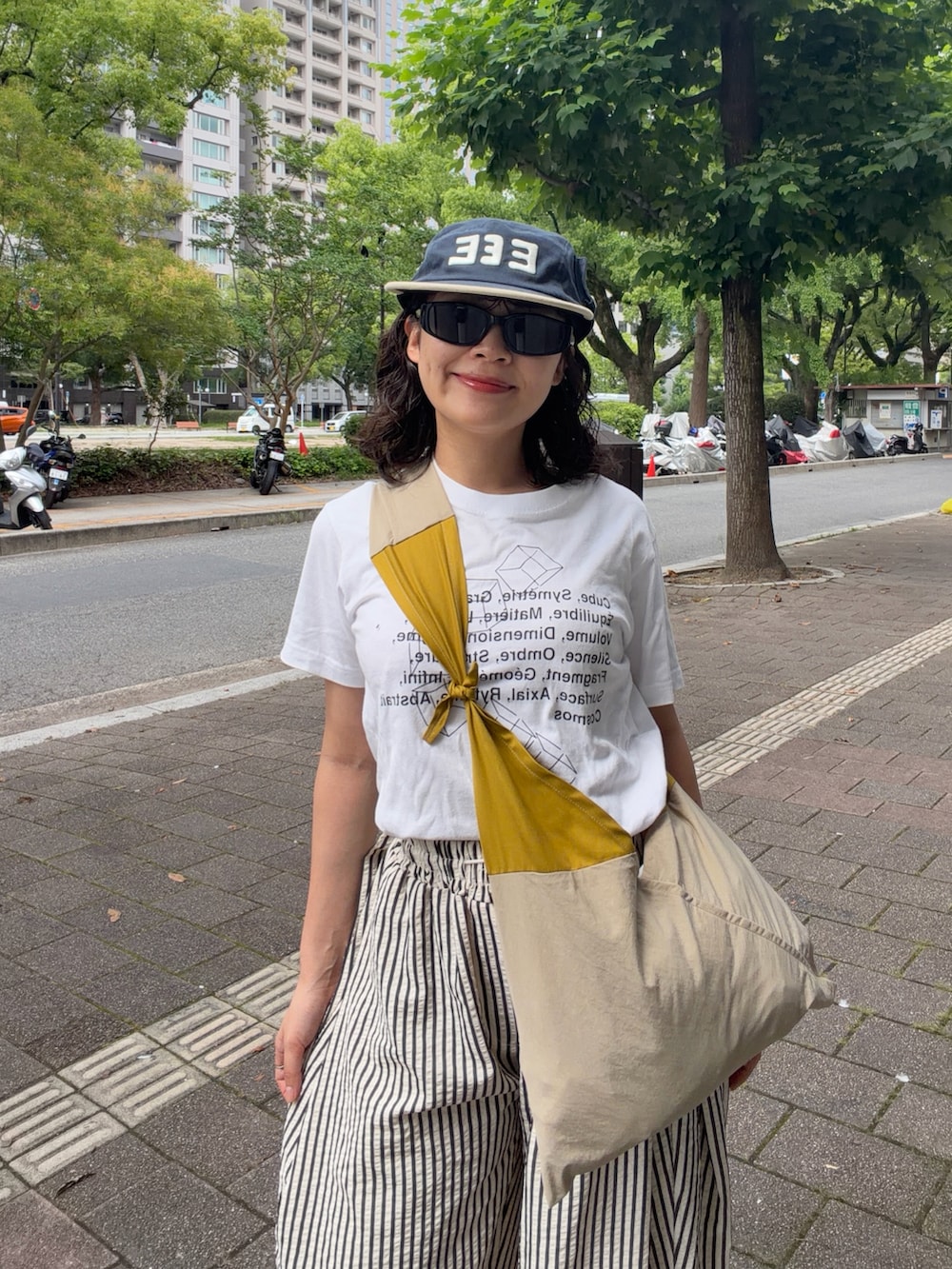イエロー系のバッグ、ホワイト系のパンツ、ベージュ系のサンダルを着用したレディースの夏コーディネートの3枚目の写真