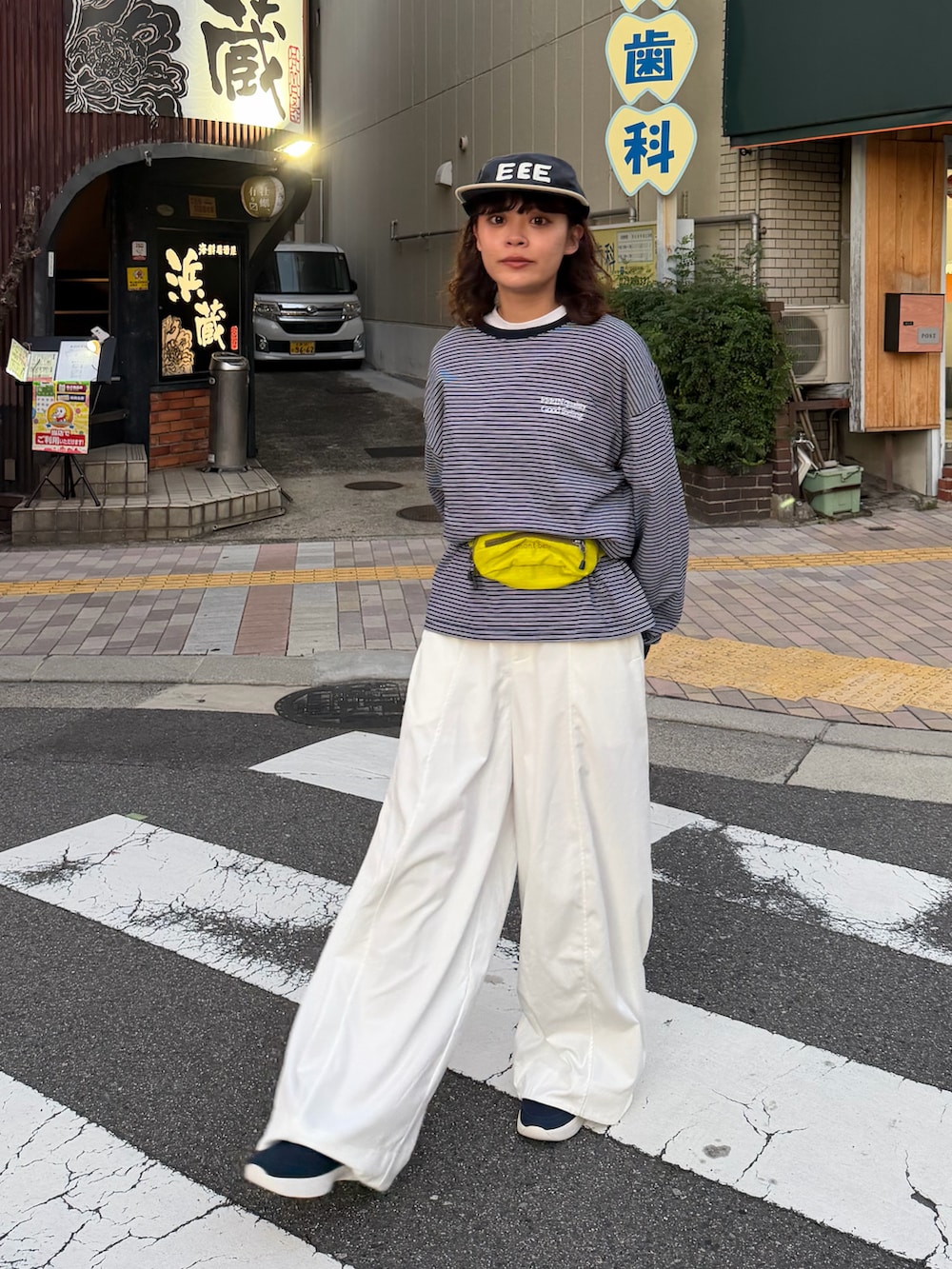 ブルー系のTシャツ/カットソー、イエロー系のバッグ、ホワイト系のパンツを着用したレディースの秋コーディネートの3枚目の写真