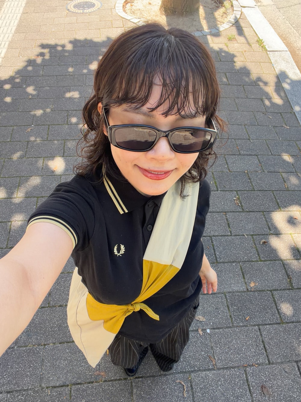 ブラック系のポロシャツ、ブラック系のスラックス、ブラック系のローファーを着用したレディースの夏コーディネートの3枚目の写真