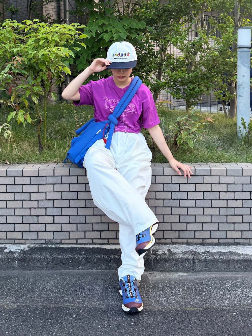 ブルー系のハンドバッグ、パープル系のTシャツ/カットソー、ホワイト系のパンツを着用したレディースの夏コーディネートの2枚目の写真