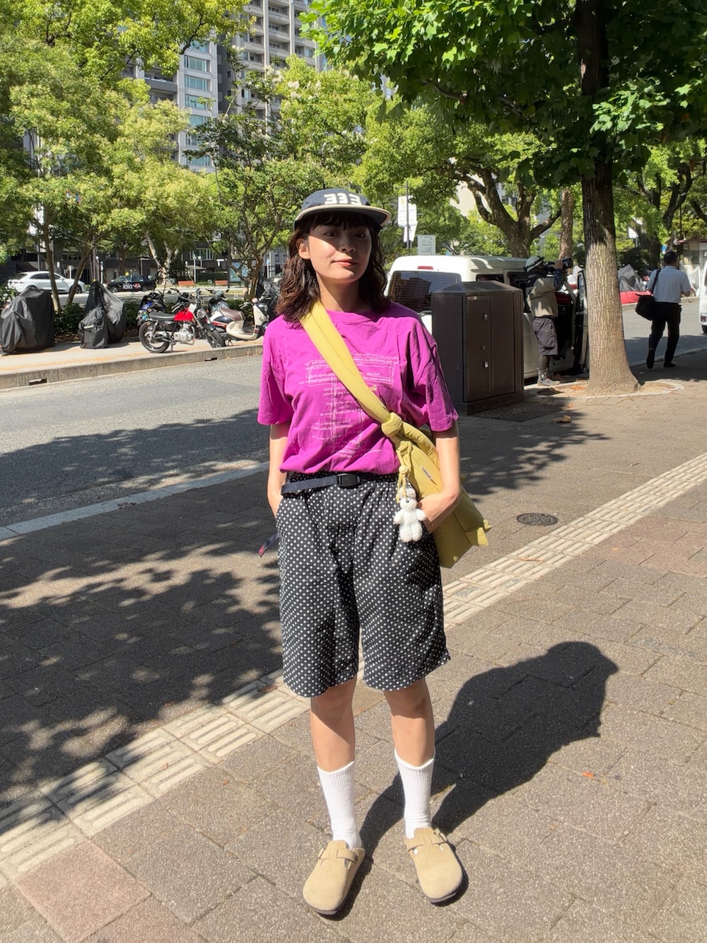 パープル系のTシャツ/カットソー、イエロー系のハンドバッグ、ブラック系のパンツを着用したレディースの夏コーディネートの2枚目の写真