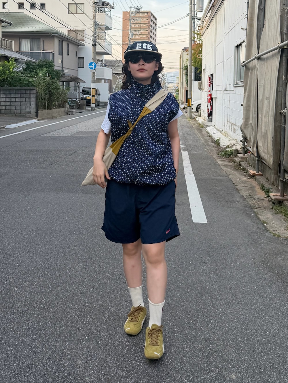 ブルー系のベスト、イエロー系のバッグ、ホワイト系のTシャツ/カットソーを着用したレディースの夏コーディネートの2枚目の写真
